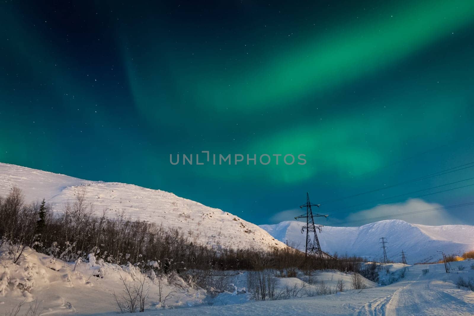 Northern Lights over snow-capped hills.