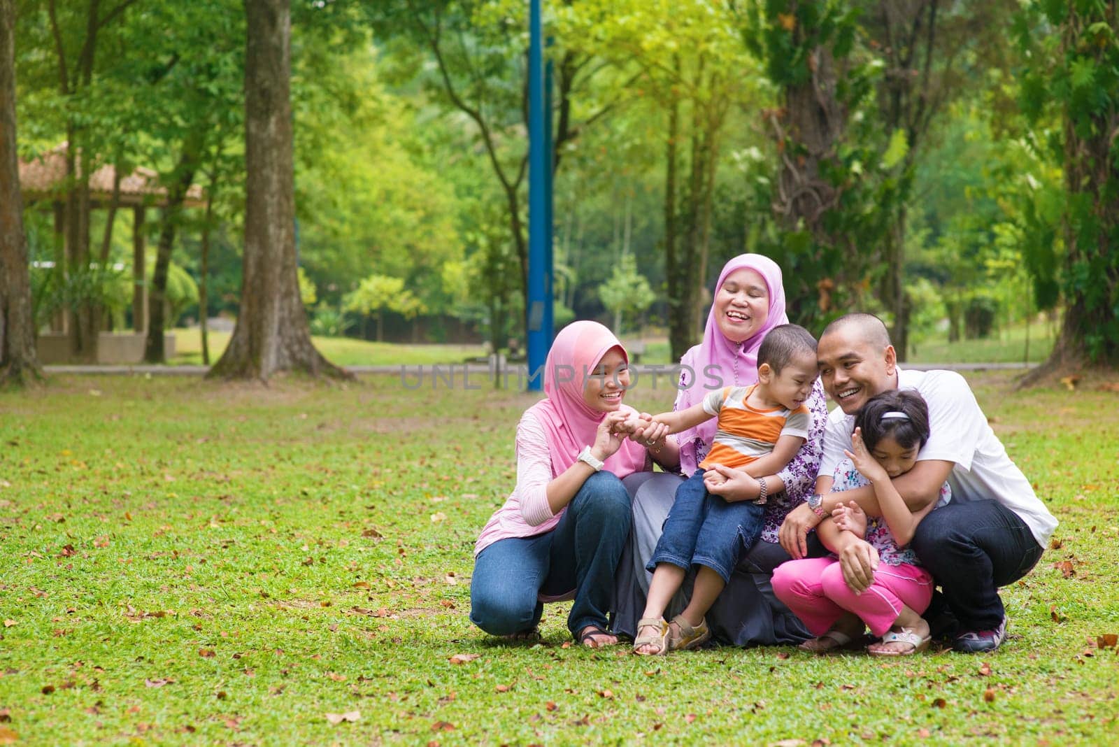 Happy family having fun at outdoor green lawn. Southeast Asian people living lifestyle.