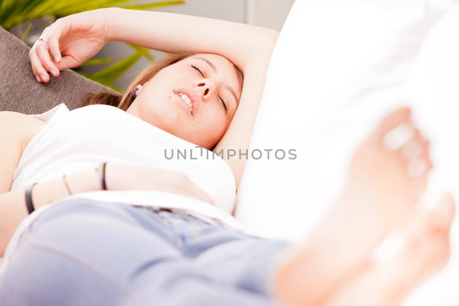 brown haired girl sleeping on her couch in a white living room