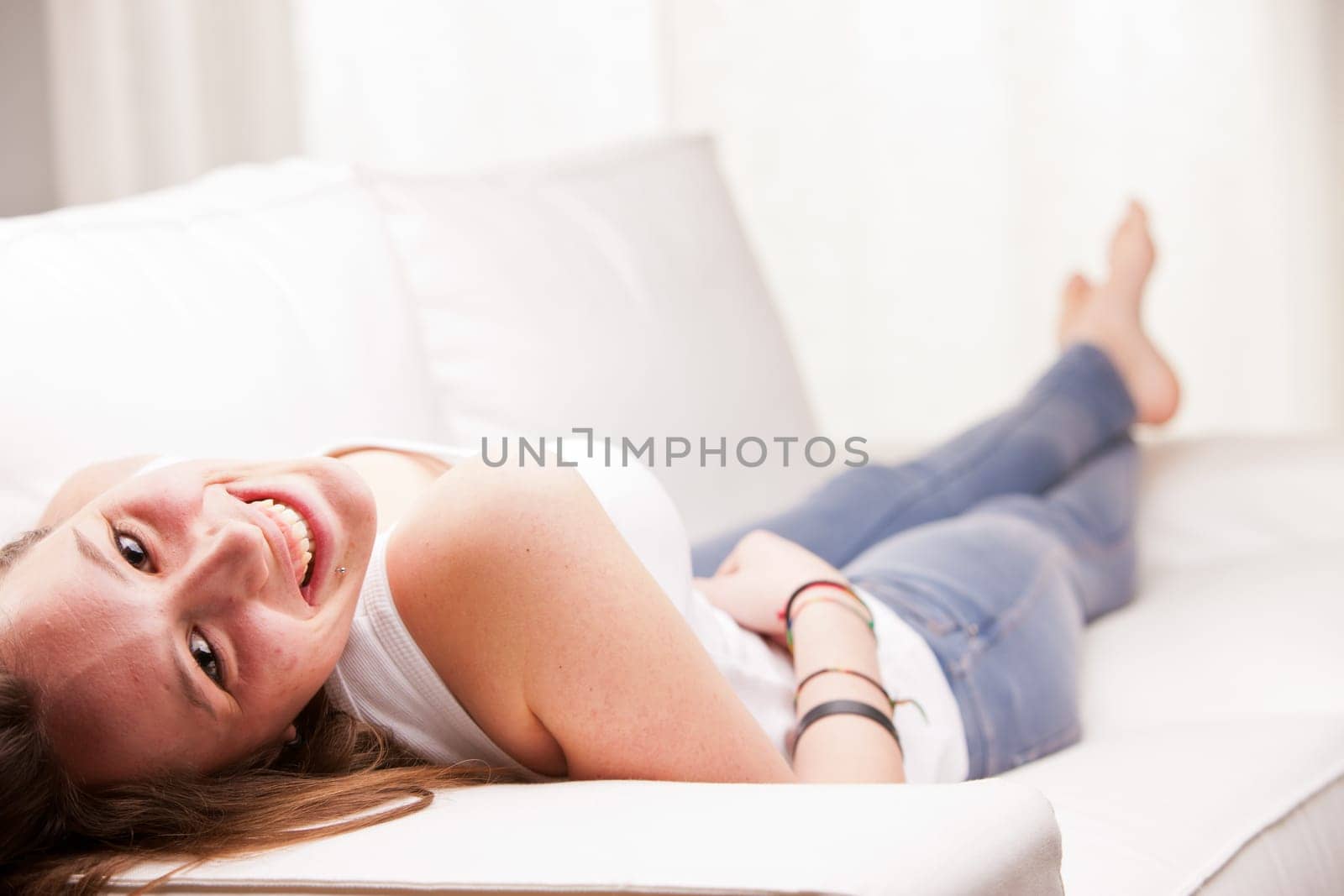 young happy brunette lying on a couch in her living room