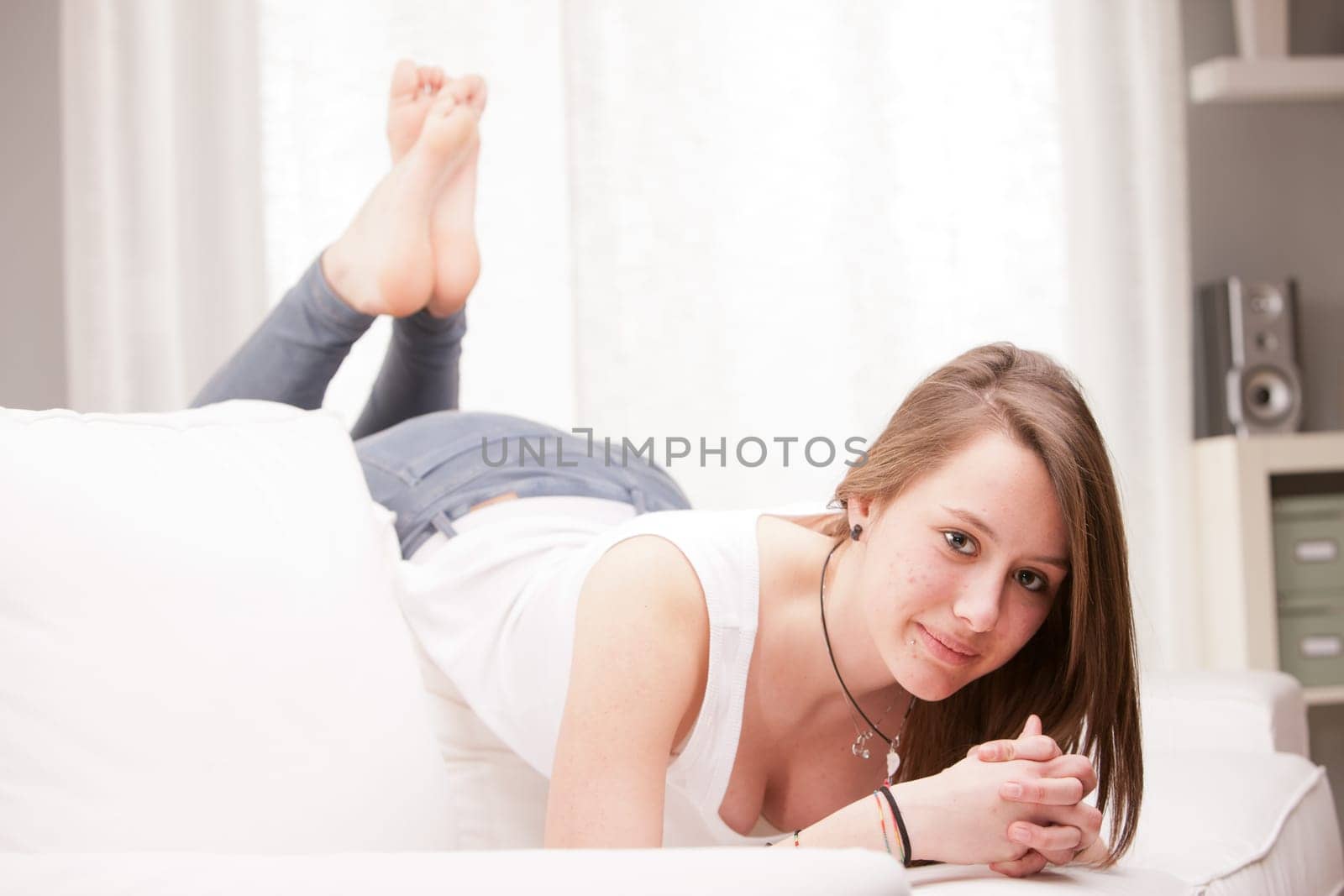 young happy brunette lying on a couch in her living room