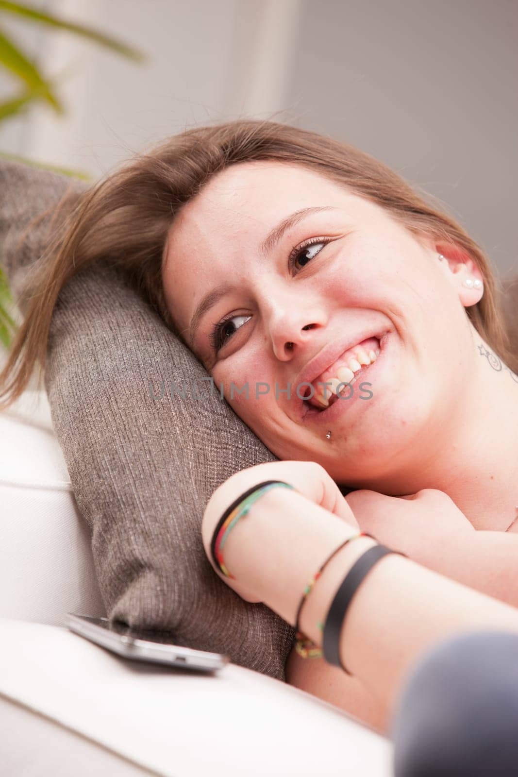 young happy brunette lying on a couch in her living room