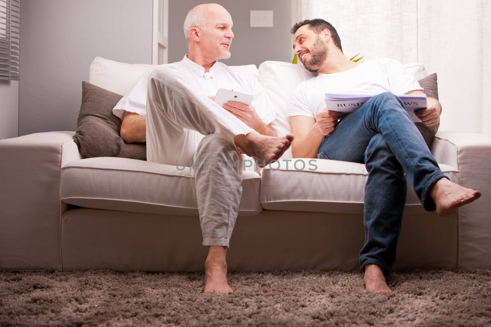 men reading on a sofa in a white living room in relax