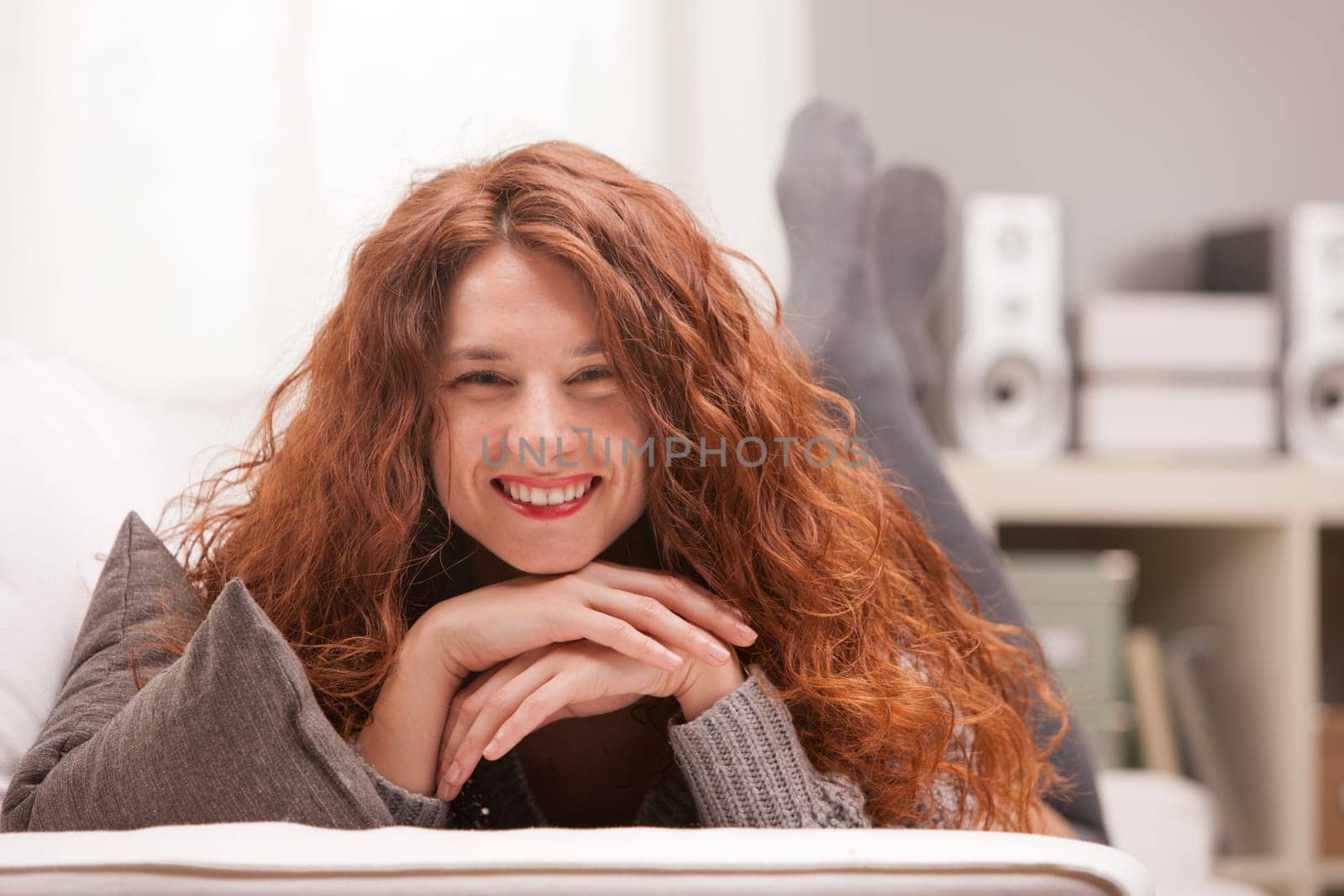 Red Headed very cute girl smiling on her sofa in her living room