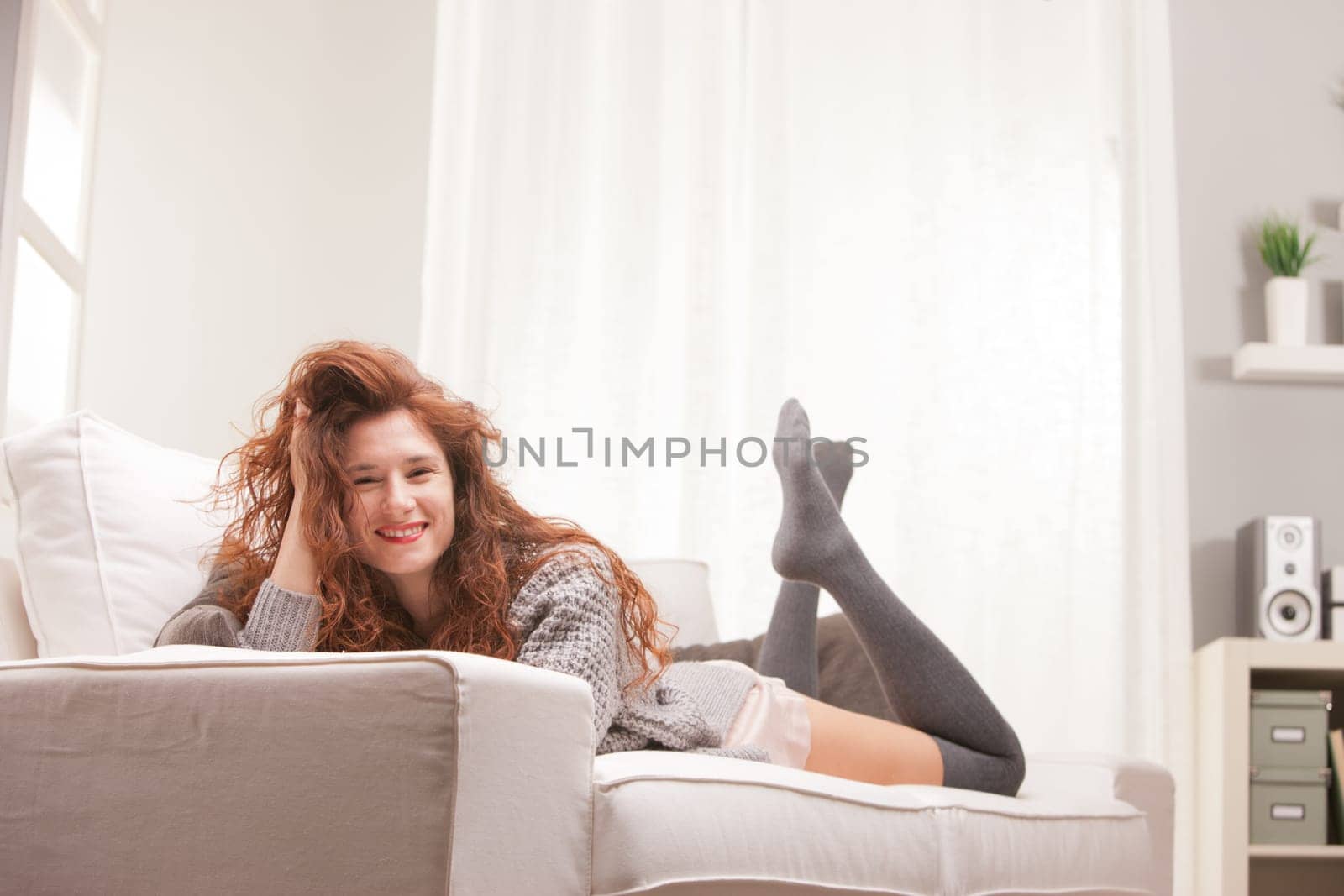 Red Headed very cute girl smiling on her sofa in her living room