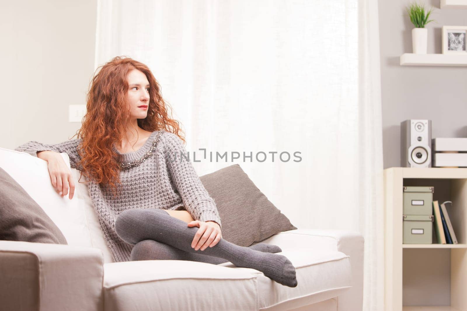 Red Headed very cute girl self-confident on her sofa in her living room