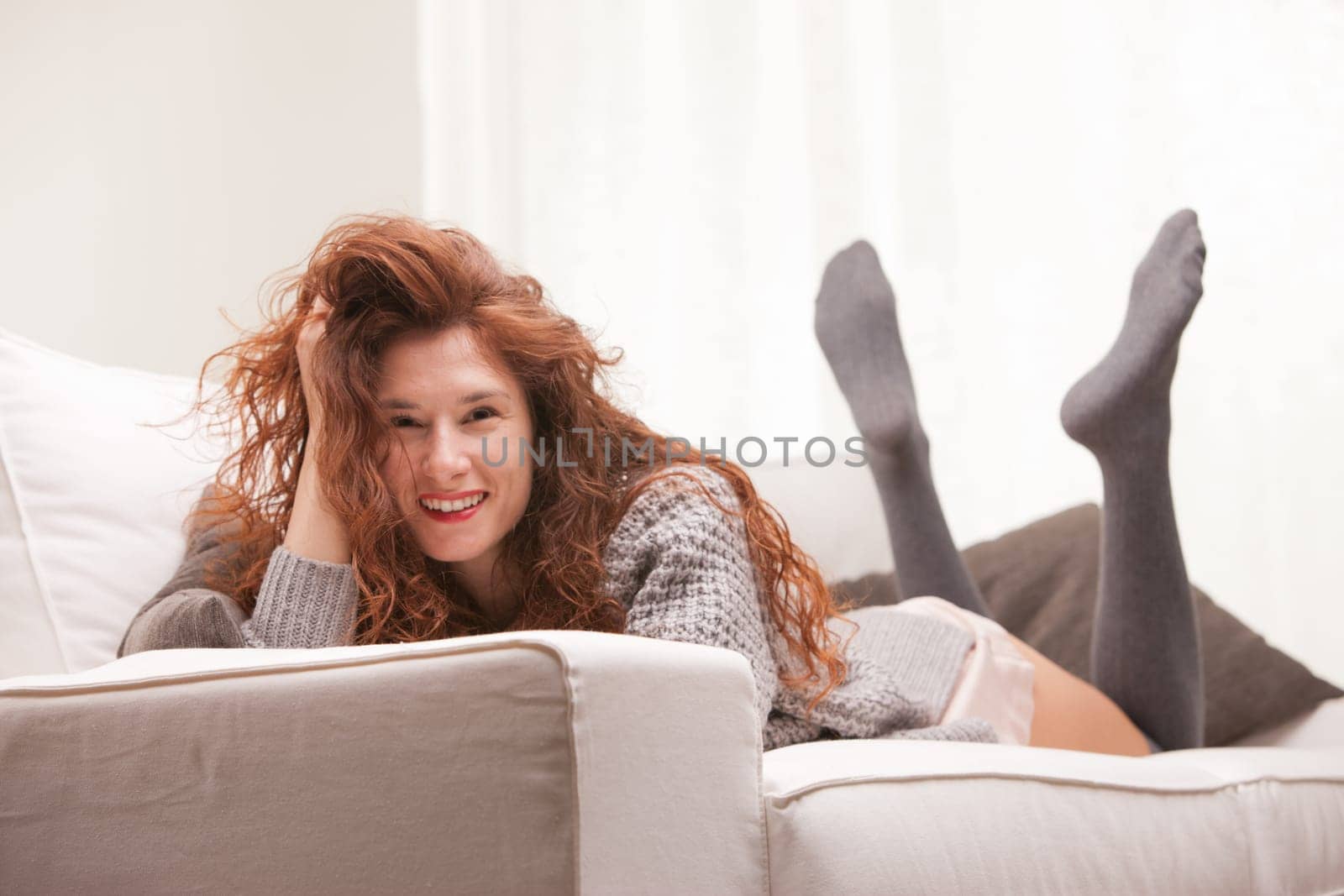 Red Headed very cute girl smiling on her sofa in her living room