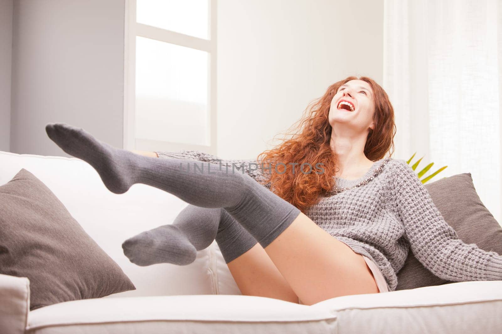 Red Headed very cute girl smiling on her sofa in her living room