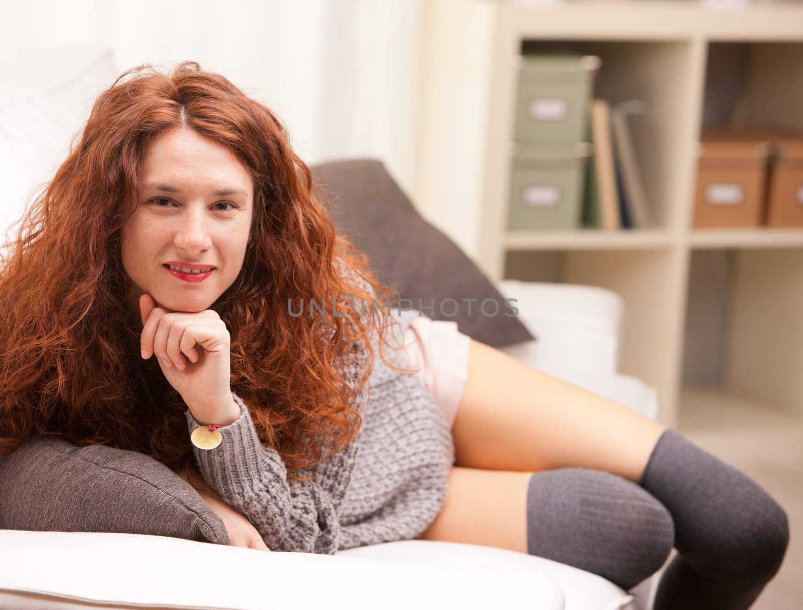 Red Headed very cute girl smiling on her sofa in her living room