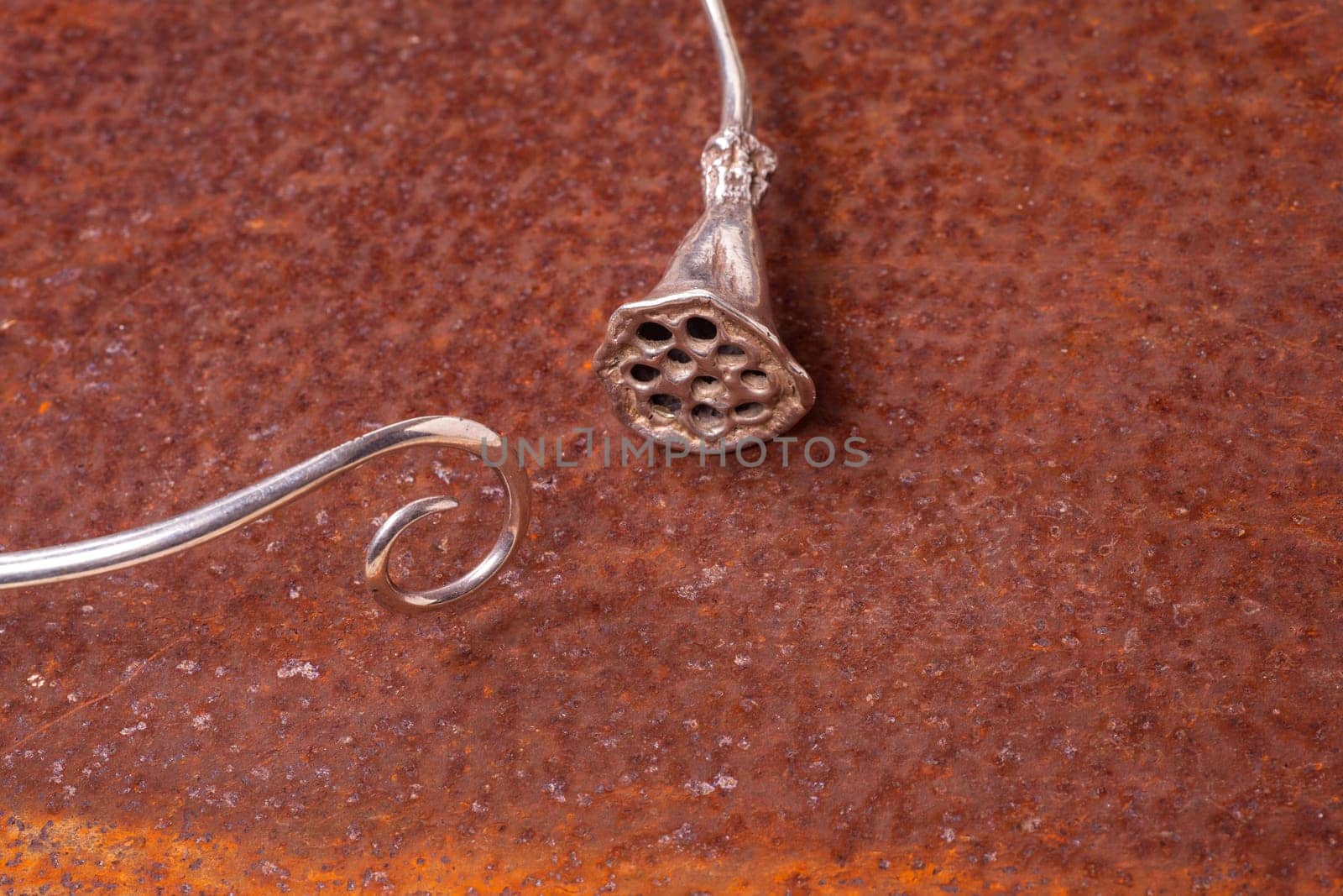 Close up of silver necklace on rusty iron, manufactured by Ornella Salamone