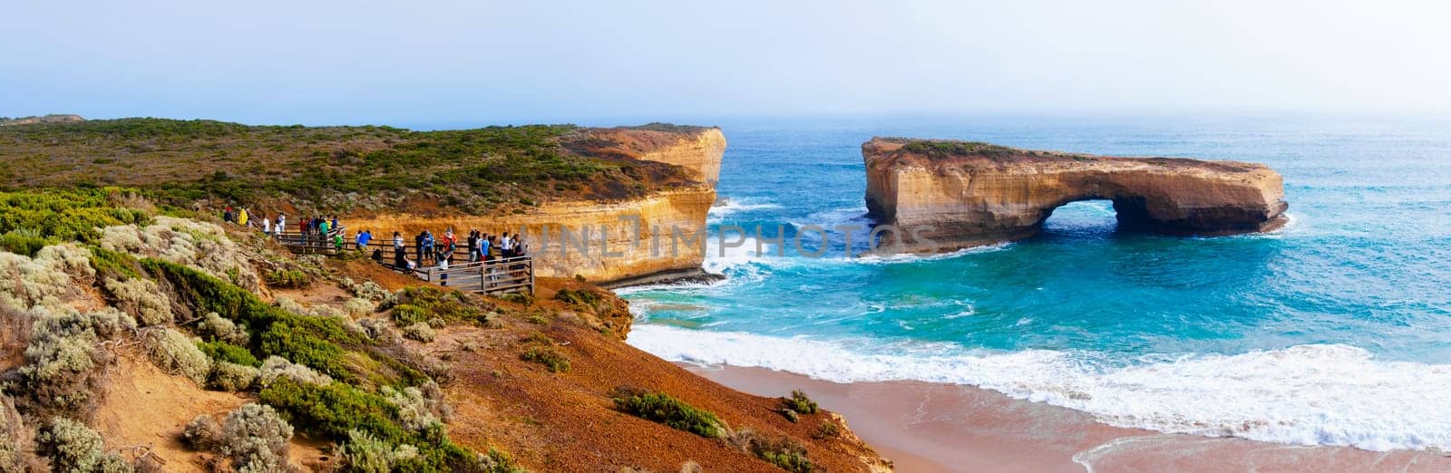 Port Campbell National Park, Victoria state, Australia - February 19, 2015: Tourists visiting the London Bridge at Twelve Apostles, a famous collection of limestone stacks off the shore of the Port Campbell National Park, by the Great Ocean Road in Victoria, Australia