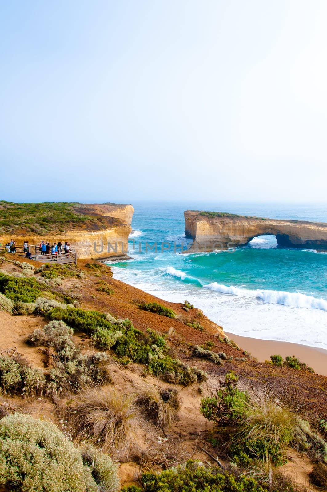 Port Campbell National Park, Victoria state, Australia - February 19, 2015: Tourists visiting the London Bridge at Twelve Apostles, a famous collection of limestone stacks off the shore of the Port Campbell National Park, by the Great Ocean Road in Victoria, Australia