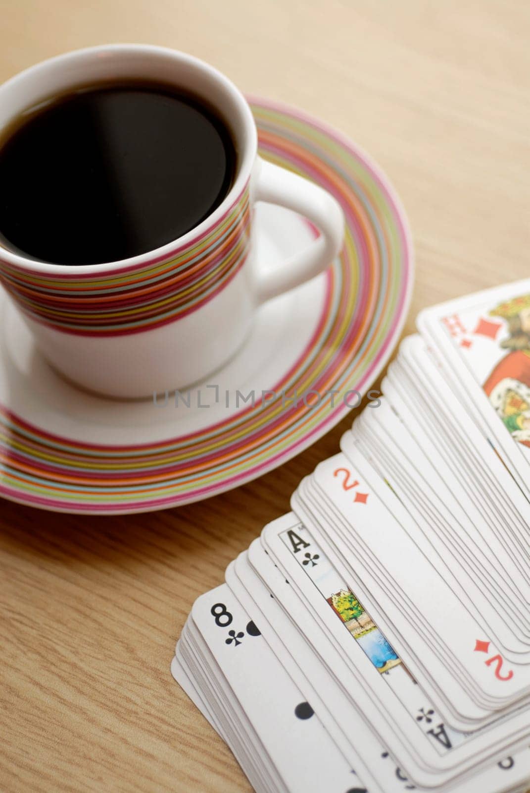High angle view of a cup of black tea with playing cards