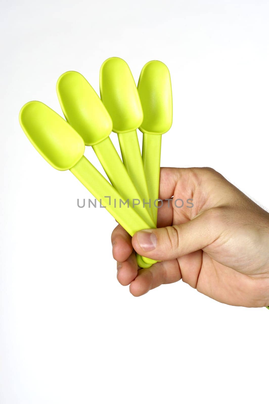 Close-up of a personŽs hand holding four plastic spoons