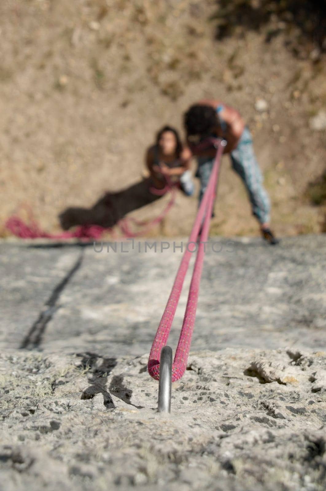 High angle view of a male rock climber scaling a rock with a female rock climber looking at him
