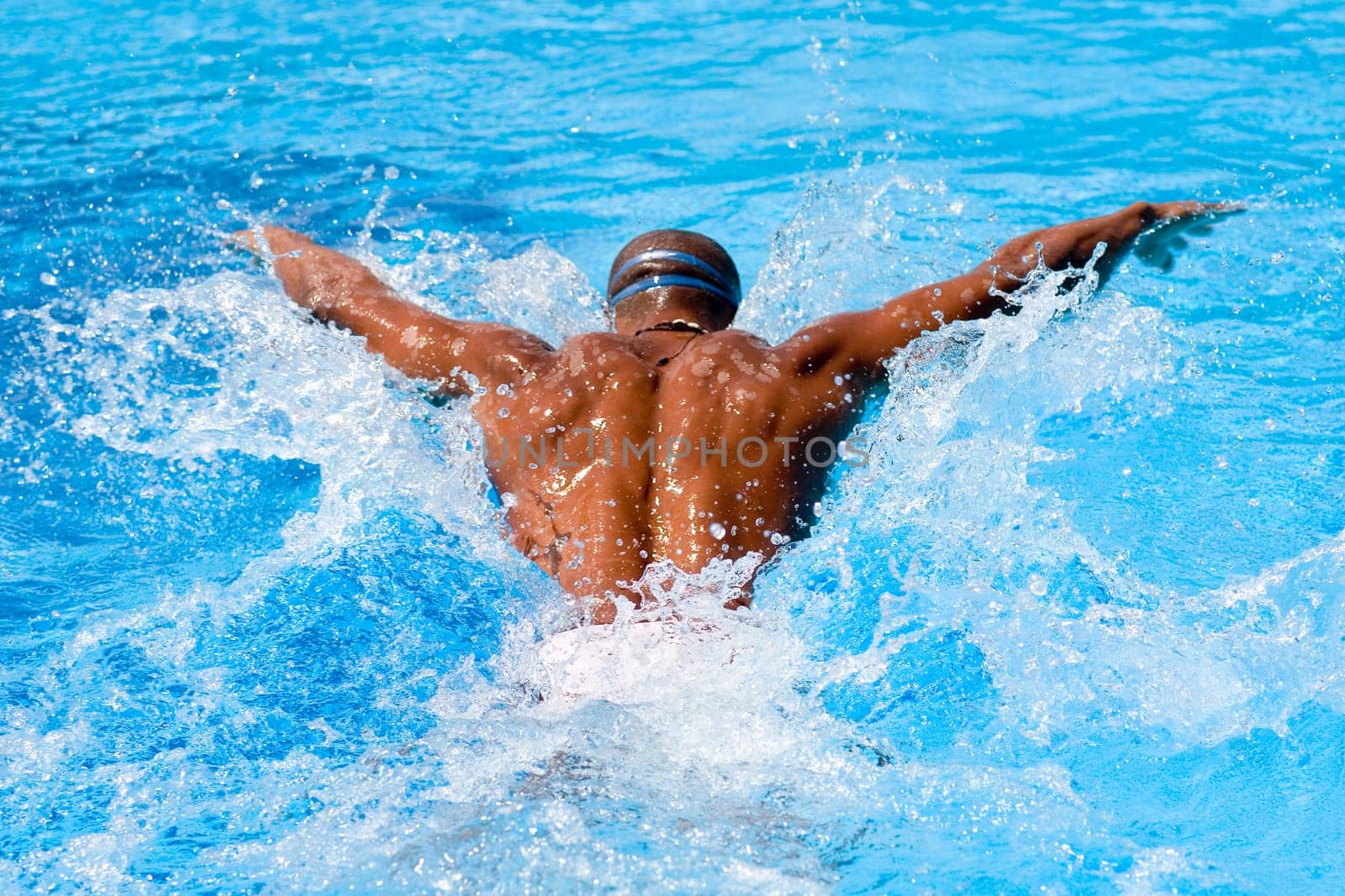Rear view of a mid adult man swimming the butterfly stroke in a swimming pool