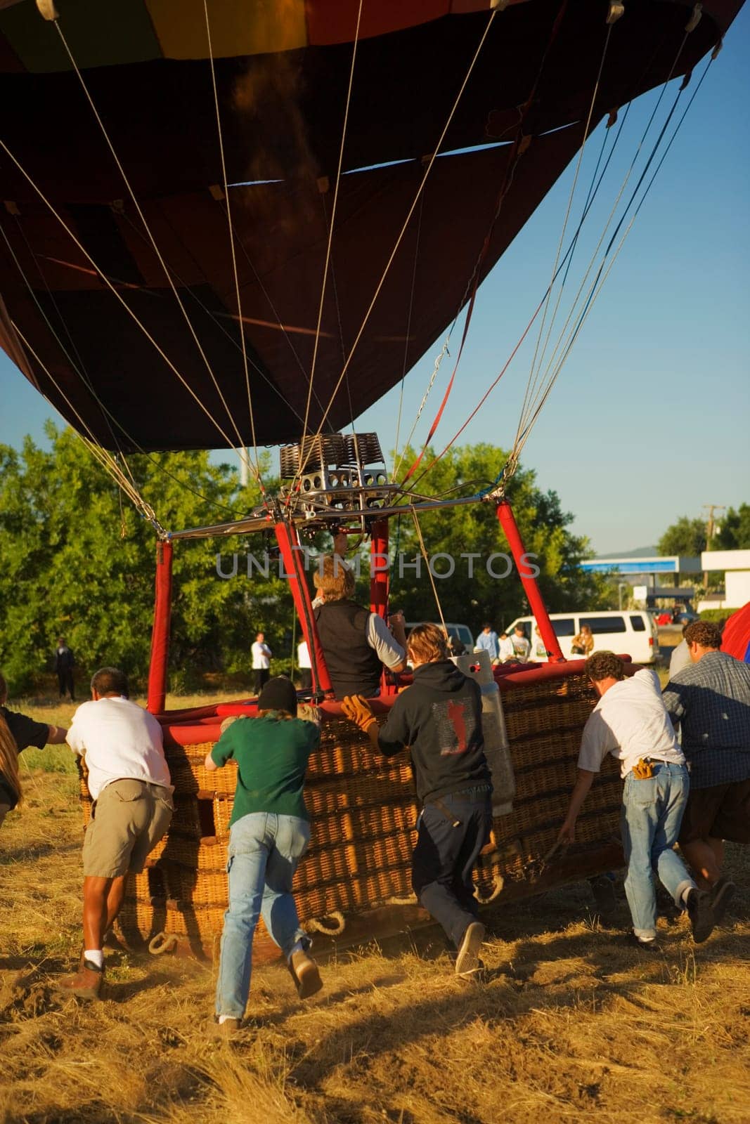 Rear view of people pulling hot air balloon