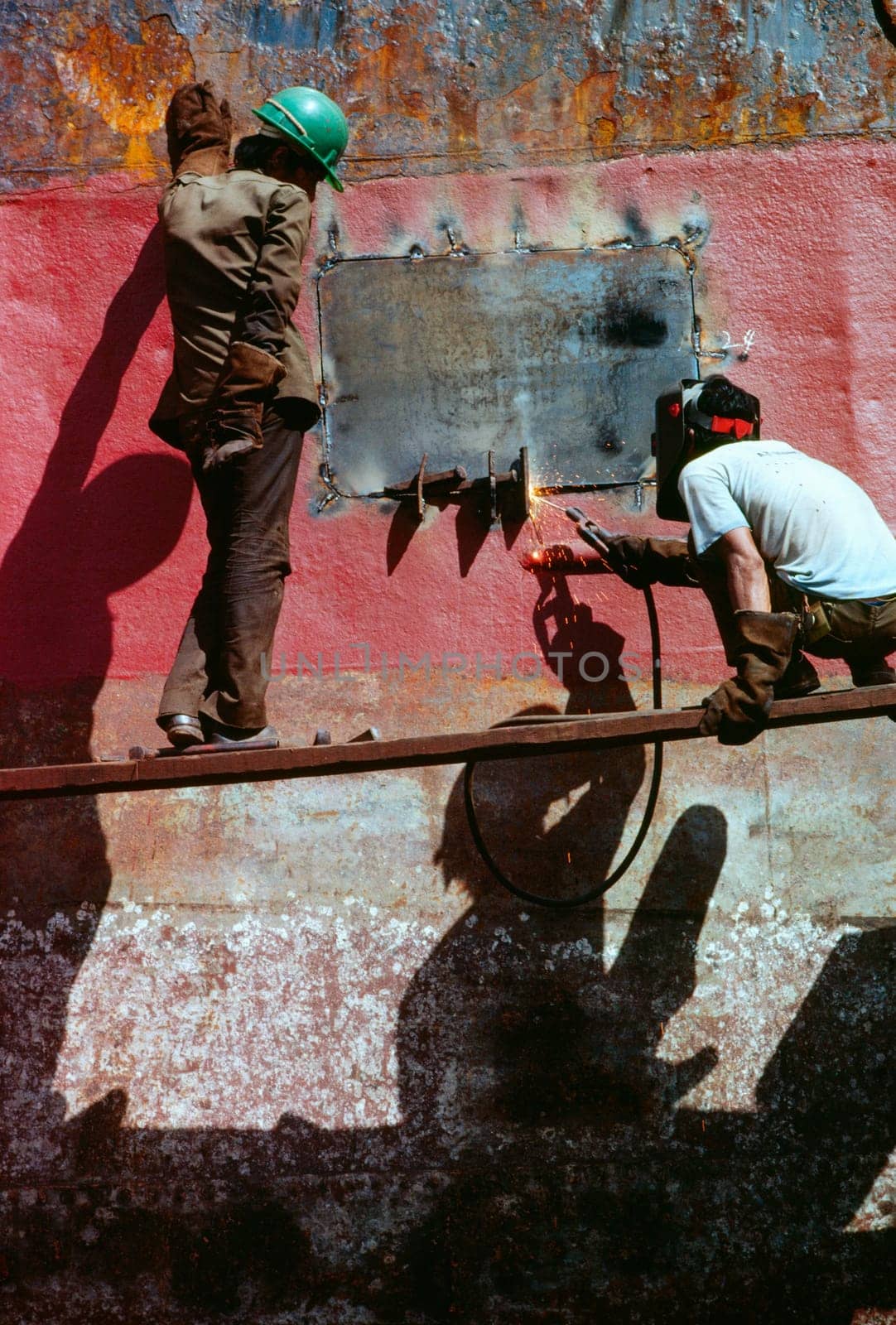 Low angle view of two men welding a tanker, Cebu, Philippines