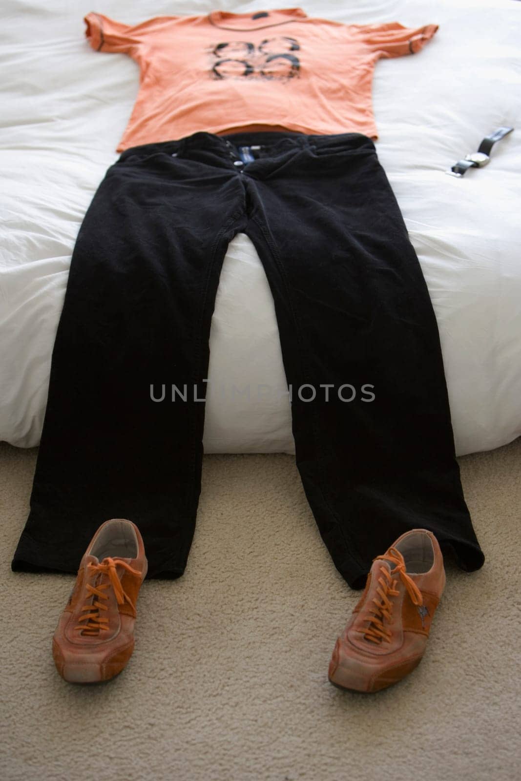 T-shirt and jeans on the bed with a pair of shoes on the floor