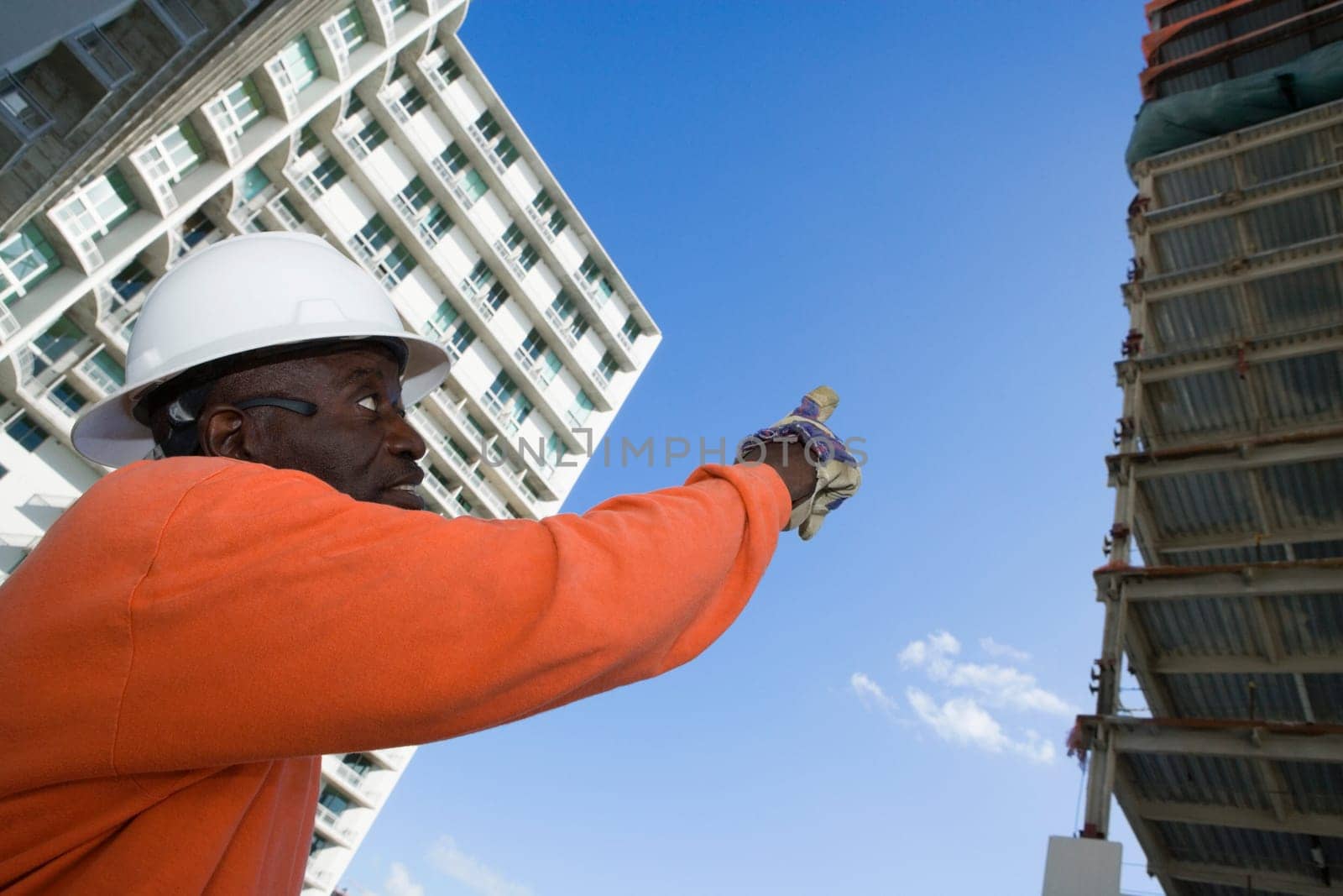 Low angle view of a male construction worker pointing towards the building
