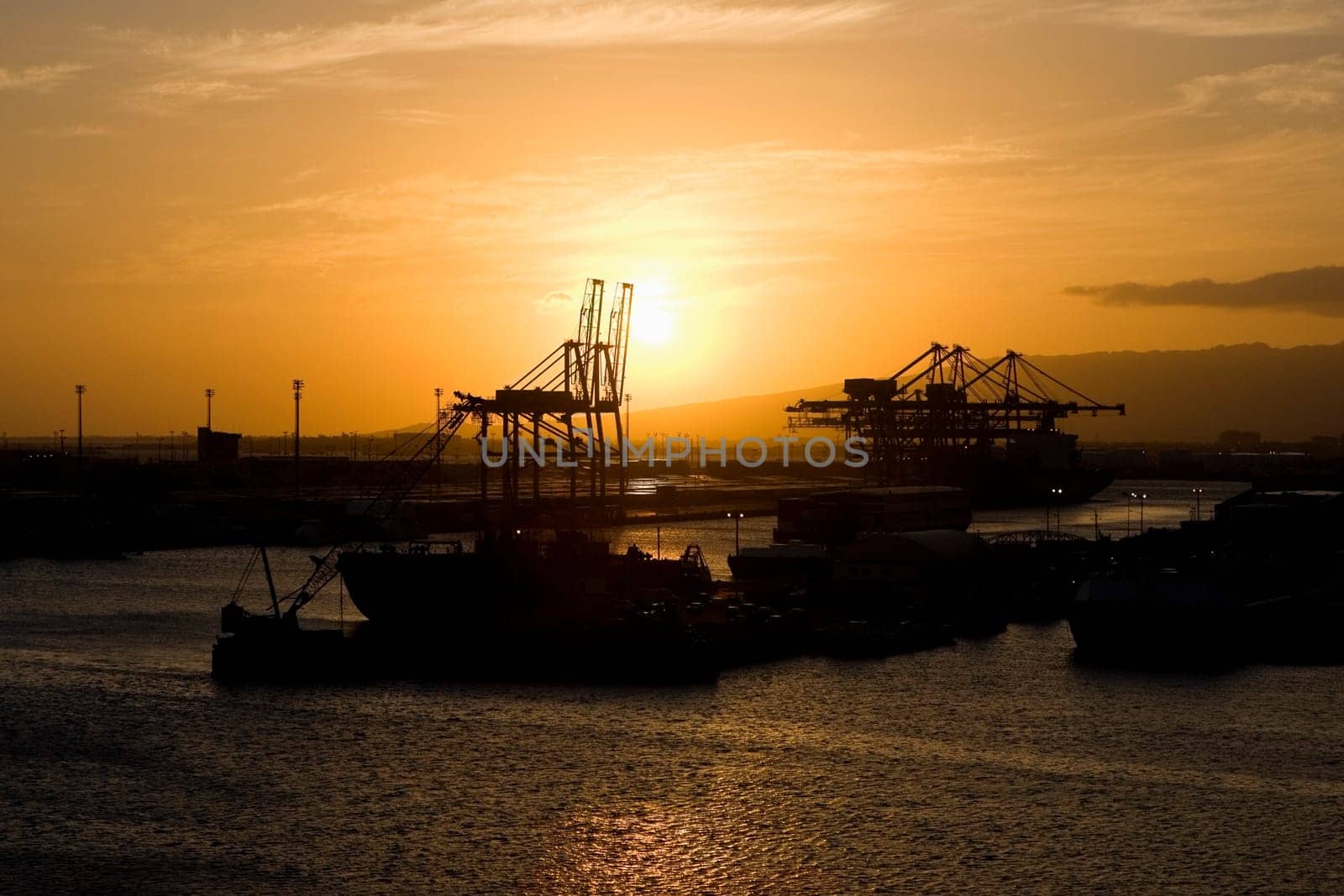 Silhouette of a container ship and cranes at a commercial dock