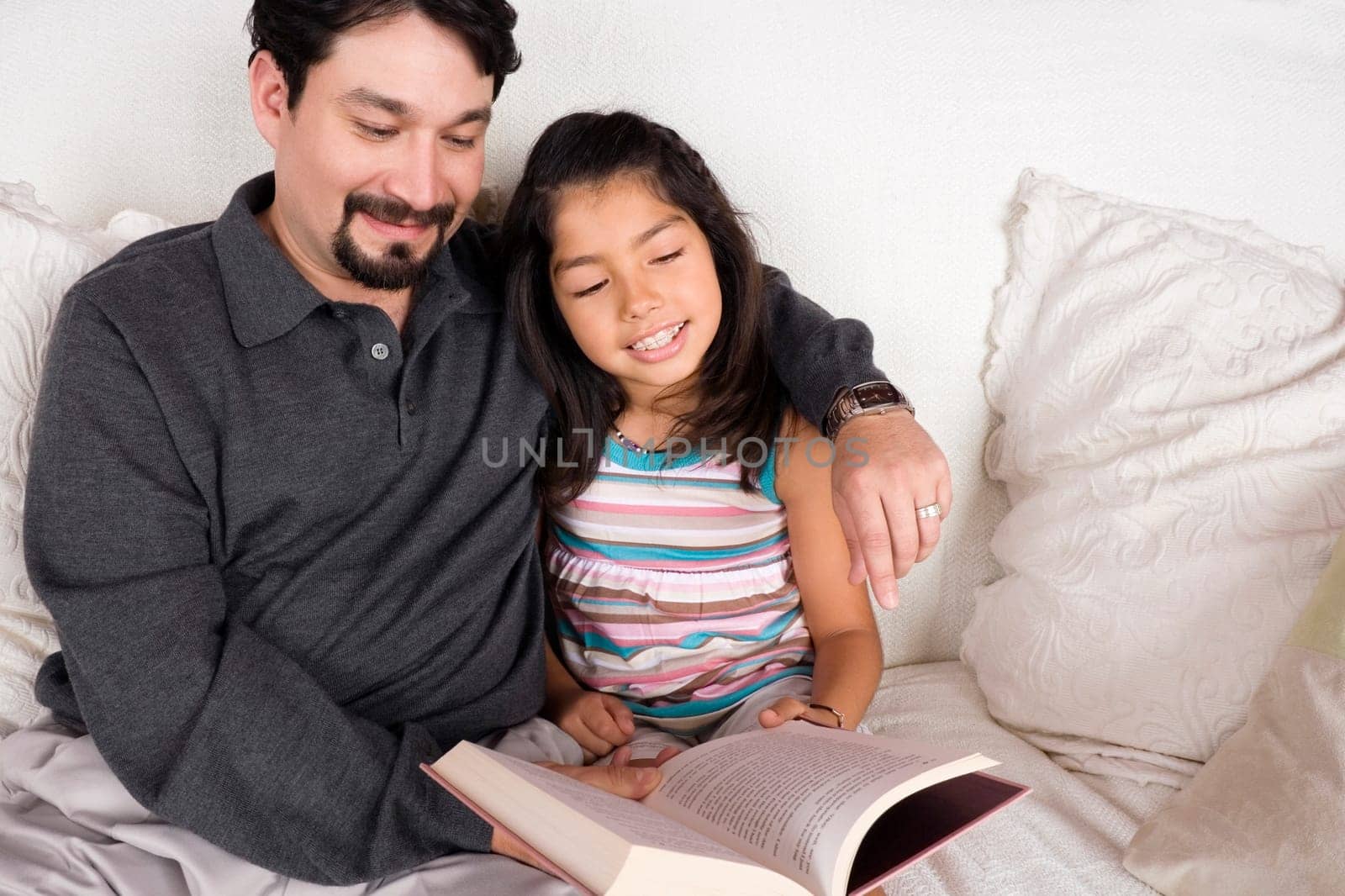 Close-up of a mid adult man and his daughter reading a book