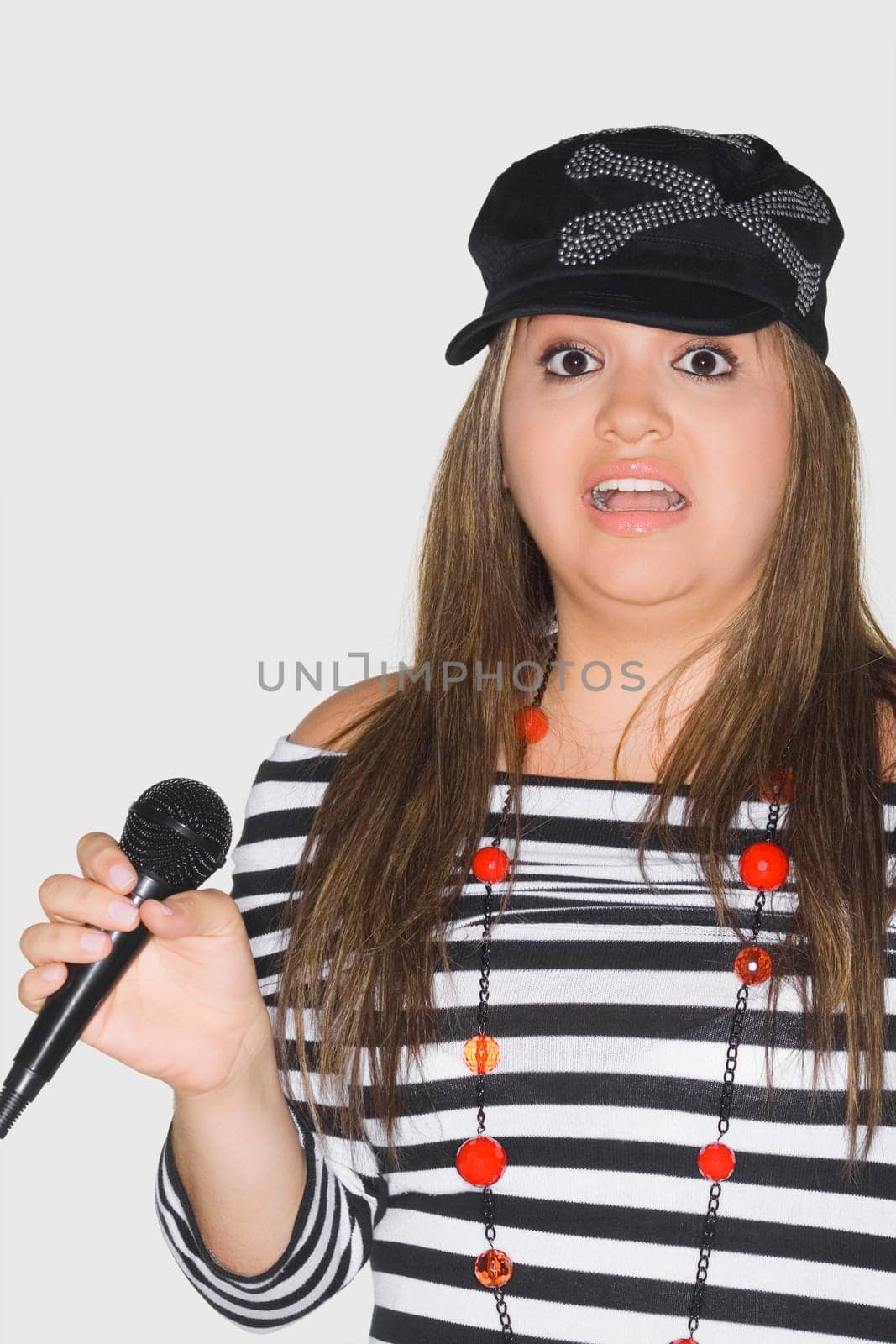 Portrait of a young woman holding a microphone and looking shocked