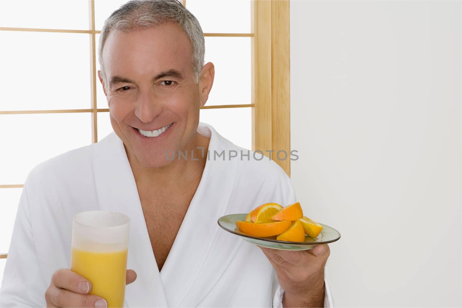 Portrait of a senior man holding a plate of oranges and a glass of orange juice