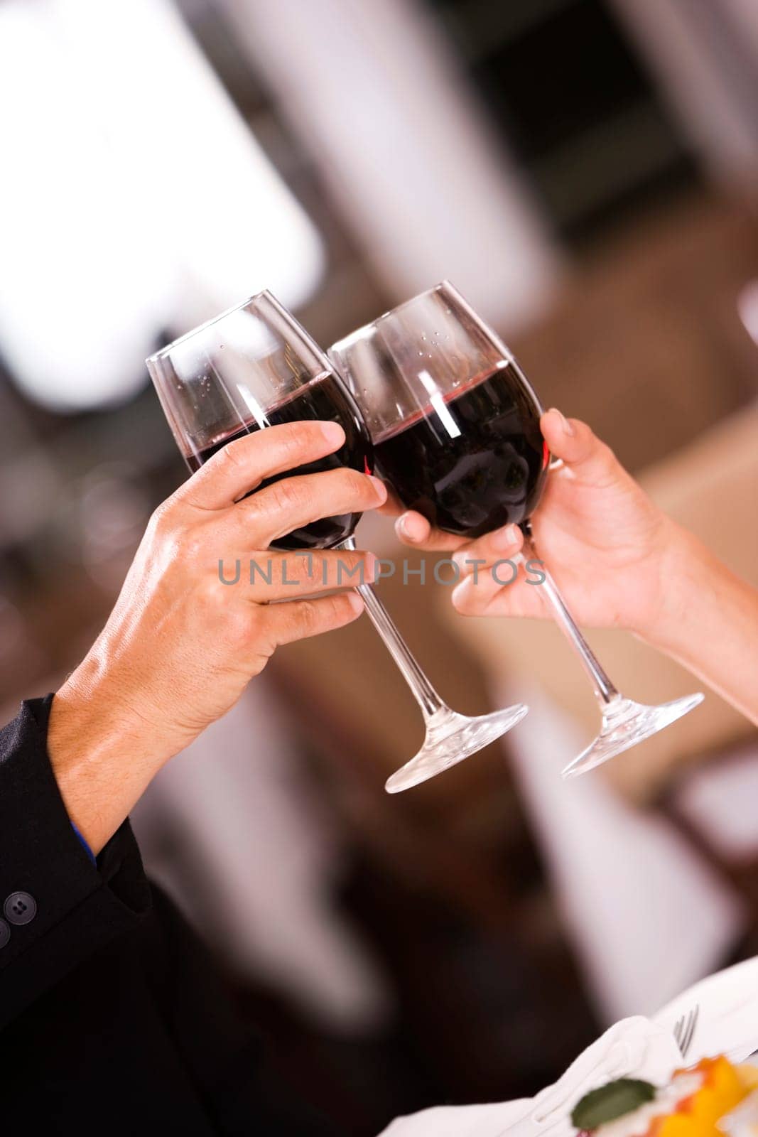 Close-up of a man and a woman toasting glasses of red wine