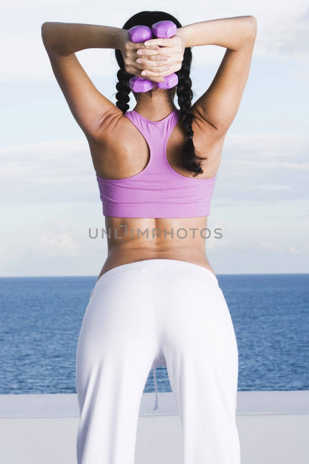 Rear view of a young woman exercising with dumbbells