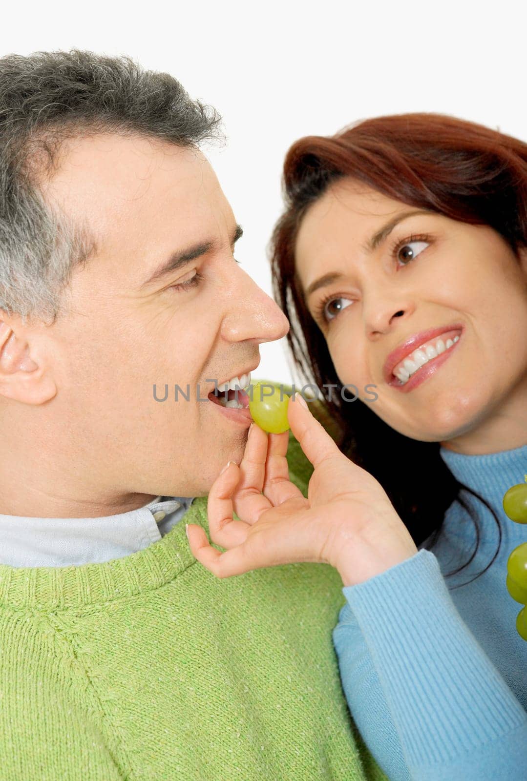 Close-up of a mid adult woman feeding a grape to a mid adult man