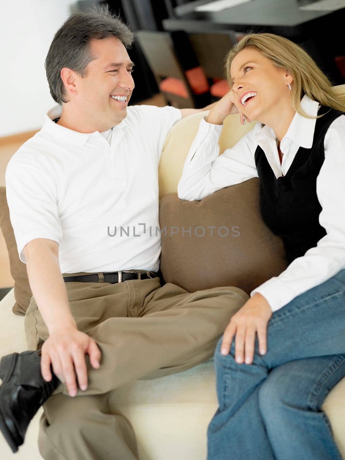 Mid adult woman and a mature man sitting on a couch and looking at each other