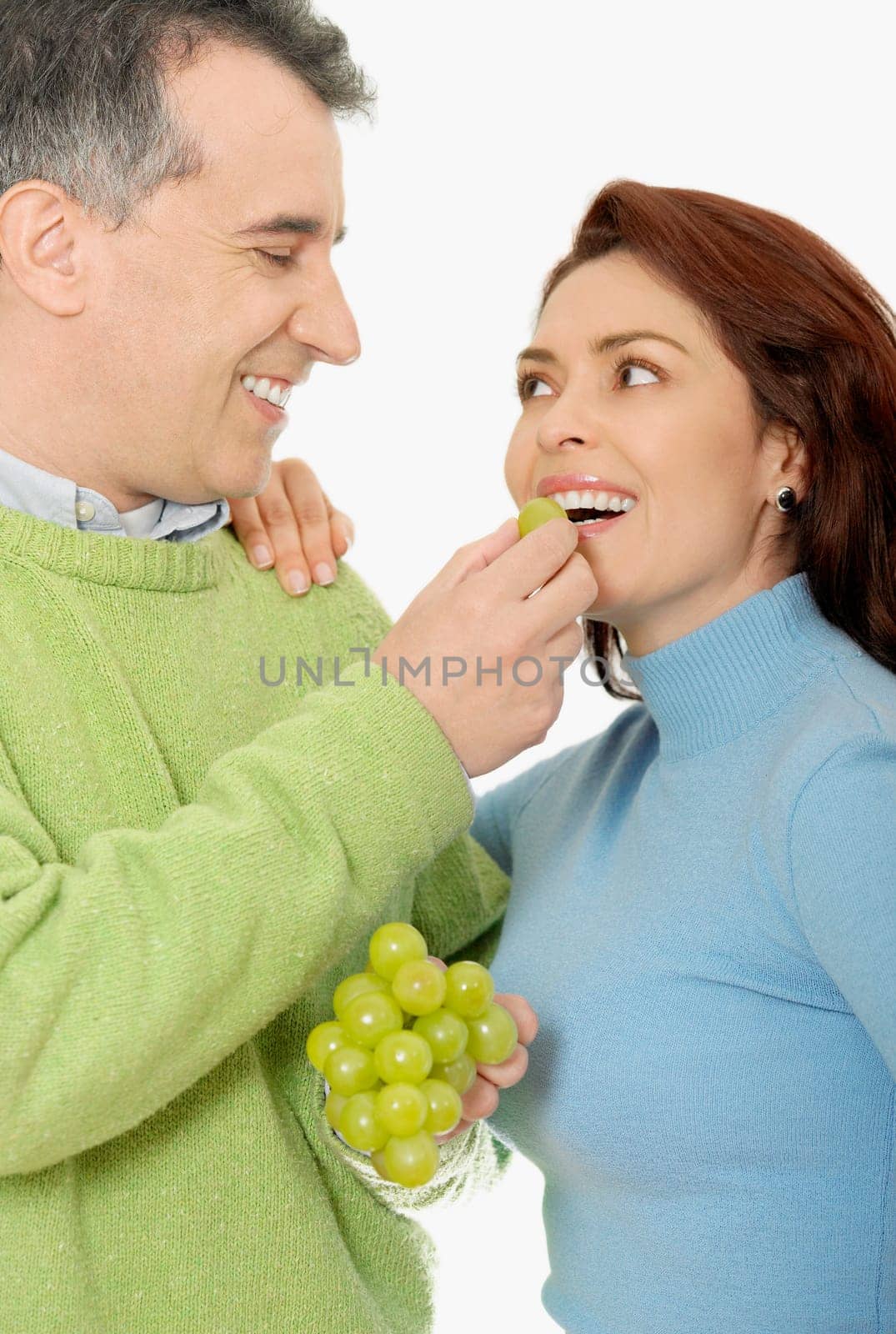 Close-up of a mid adult man feeding a grape to a mid adult woman