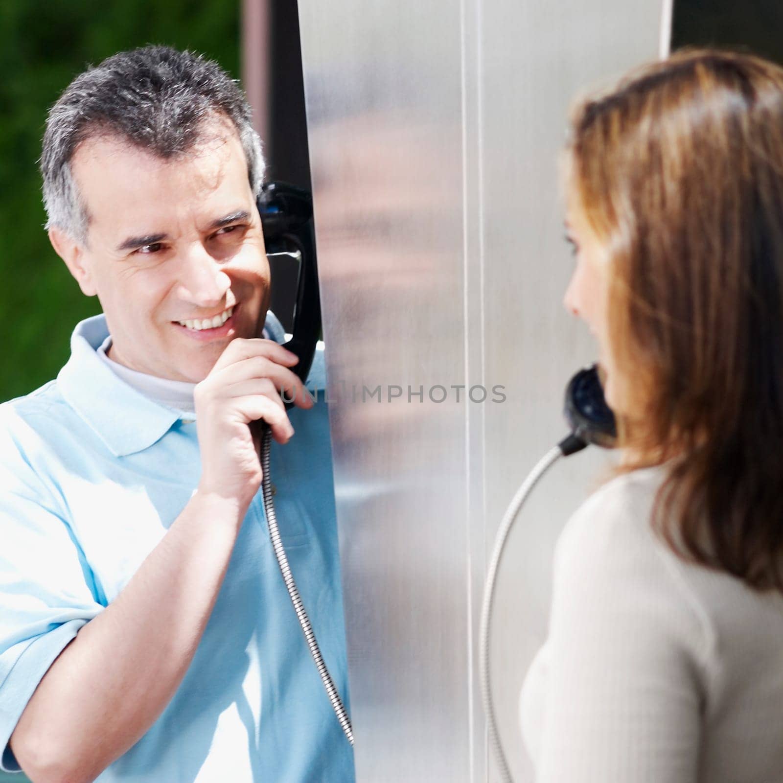 Close-up of a mid adult couple talking on a pay phone
