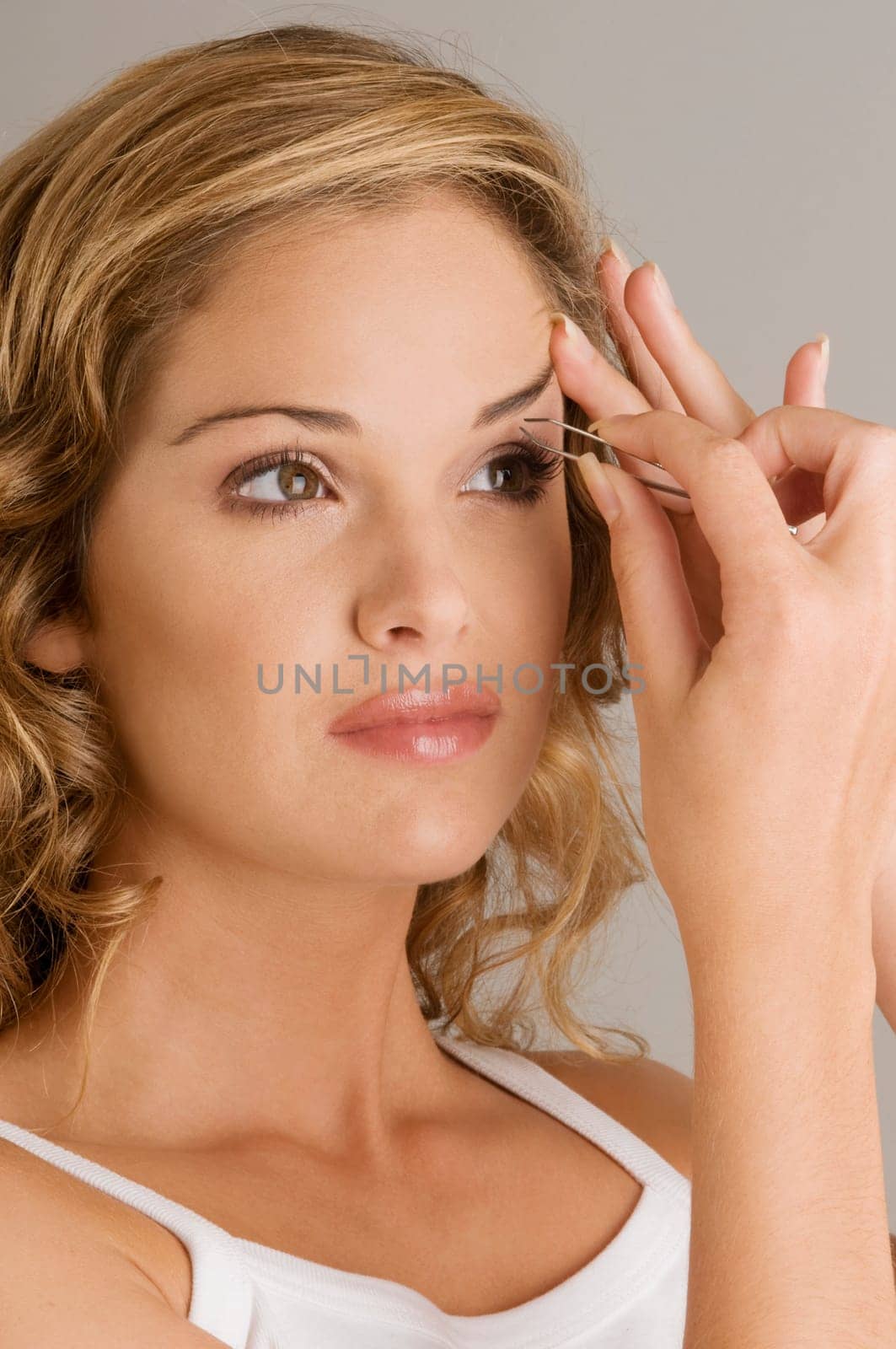 Close_up of a young woman tweezing her eyebrow