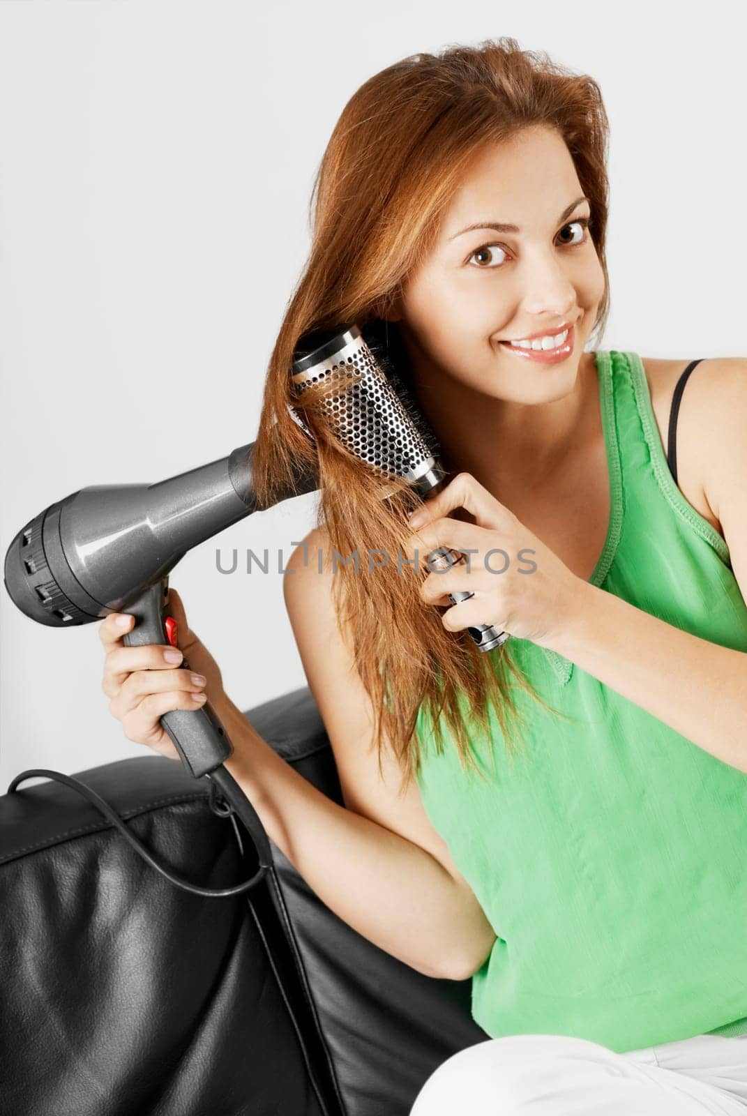 Portrait of a young woman drying her hair with a hair dryer