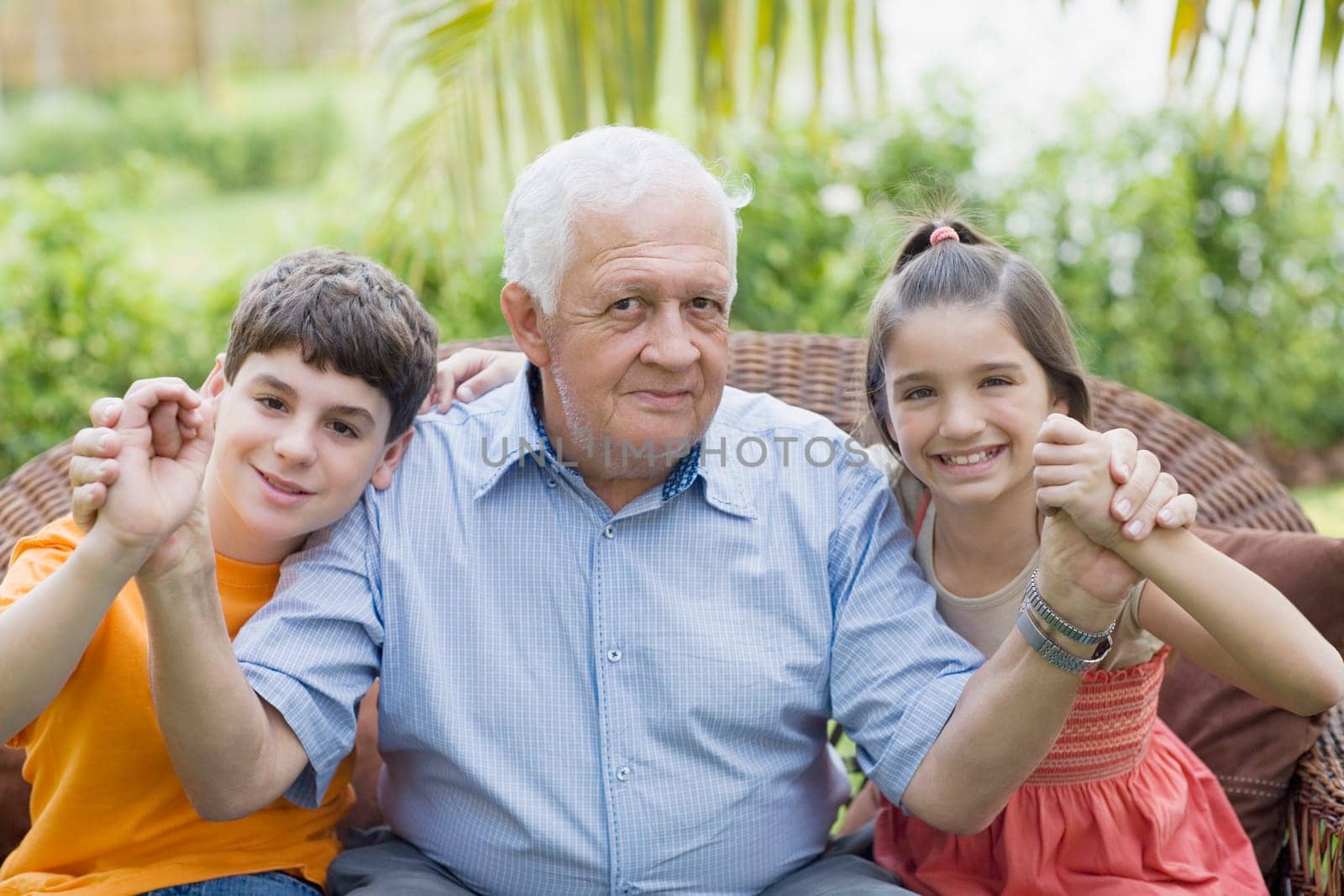 Portrait of a senior man holding his grandchildrenŽs hands and smiling