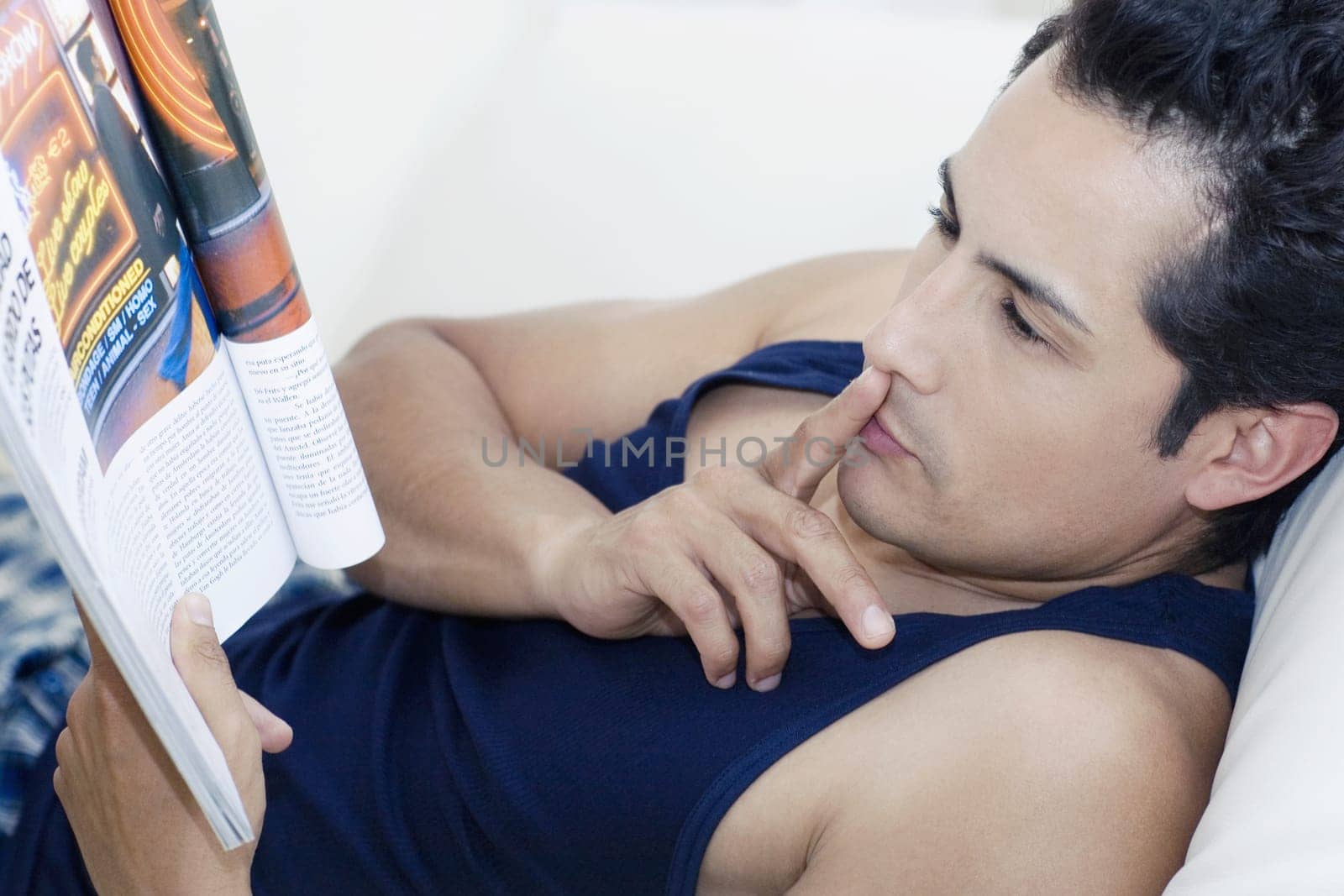 Side profile of a young man reading a magazine with his finger on his lips