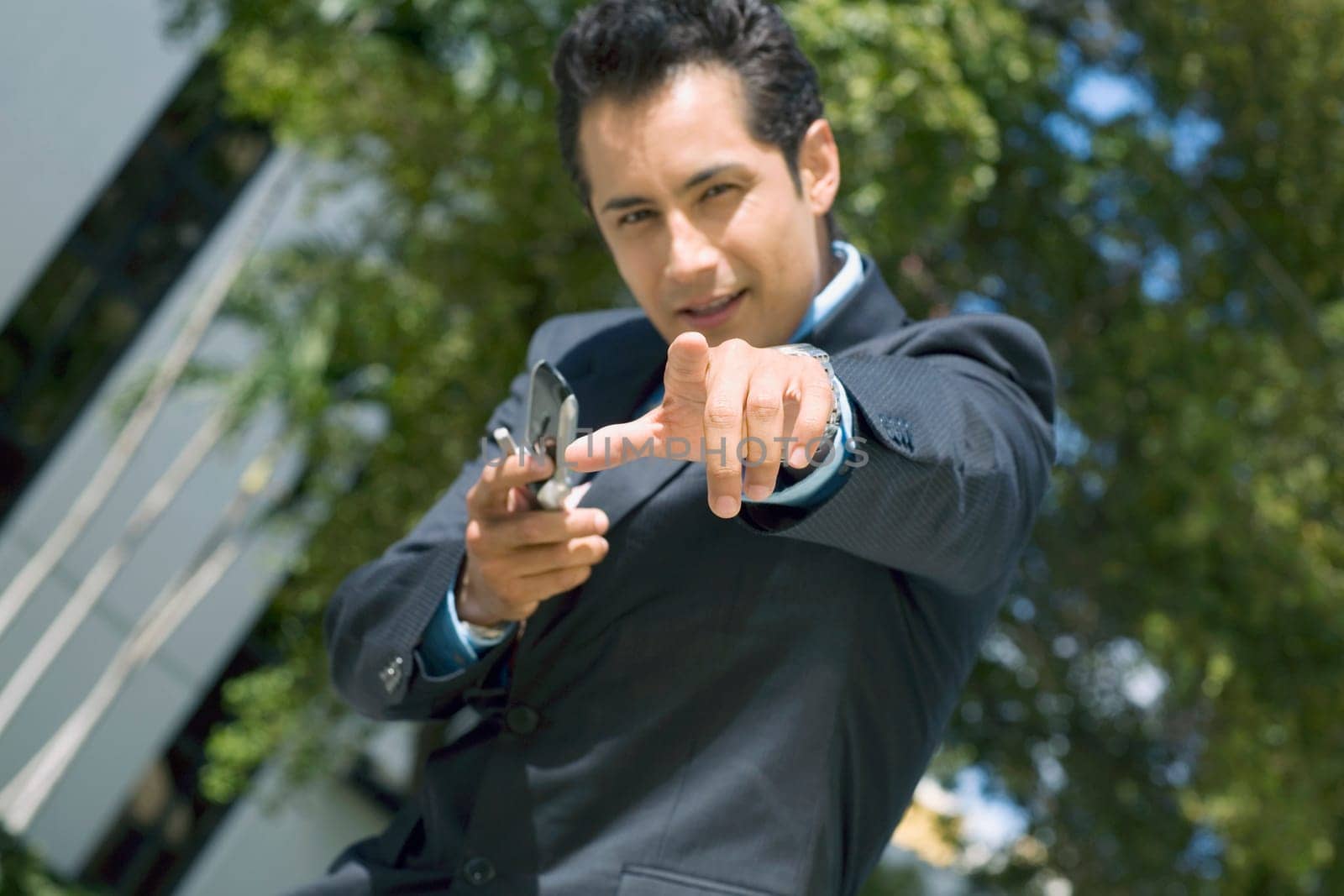 Portrait of a businessman holding a mobile phone and pointing forward
