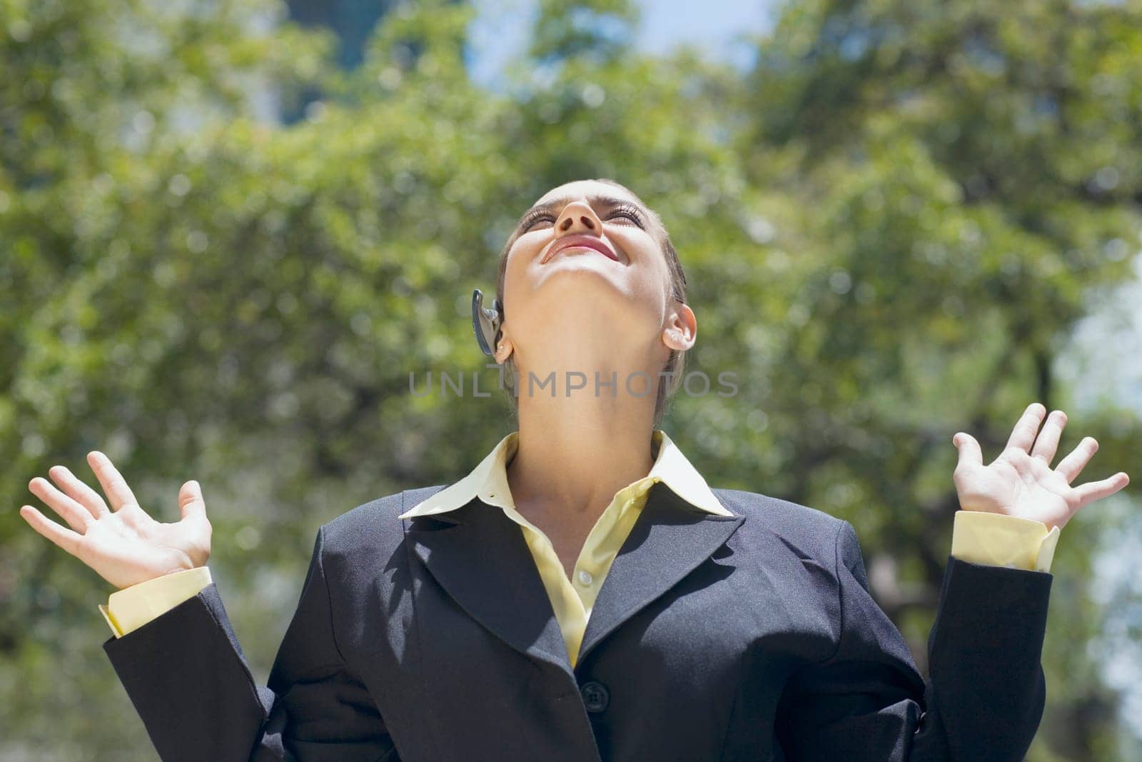 Businesswoman looking up with her arms raised