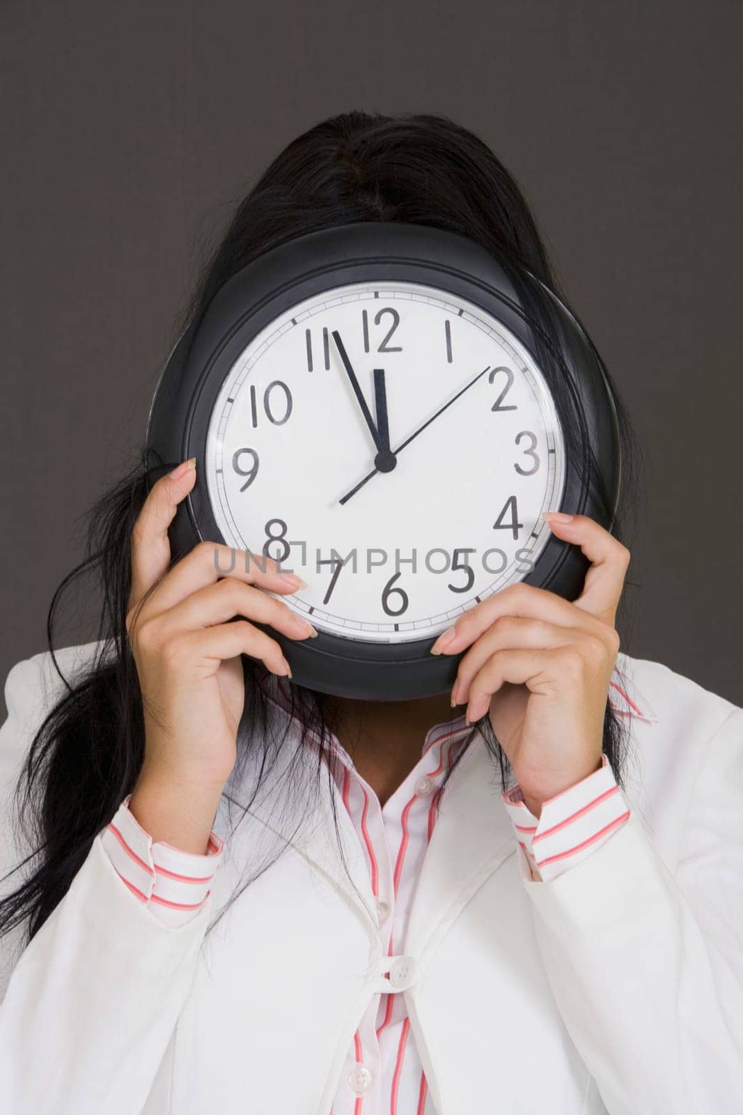 Close-up of a businesswoman holding a clock in front of her face