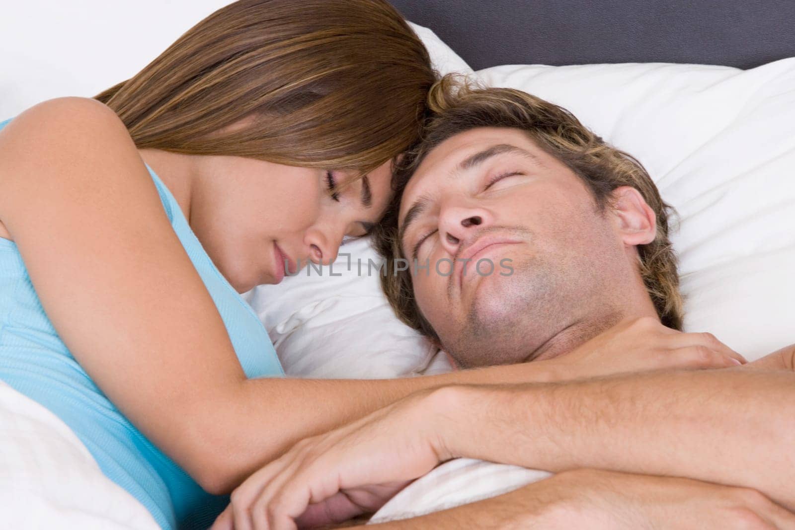 Close-up of a mid adult man sleeping on the bed with a young woman