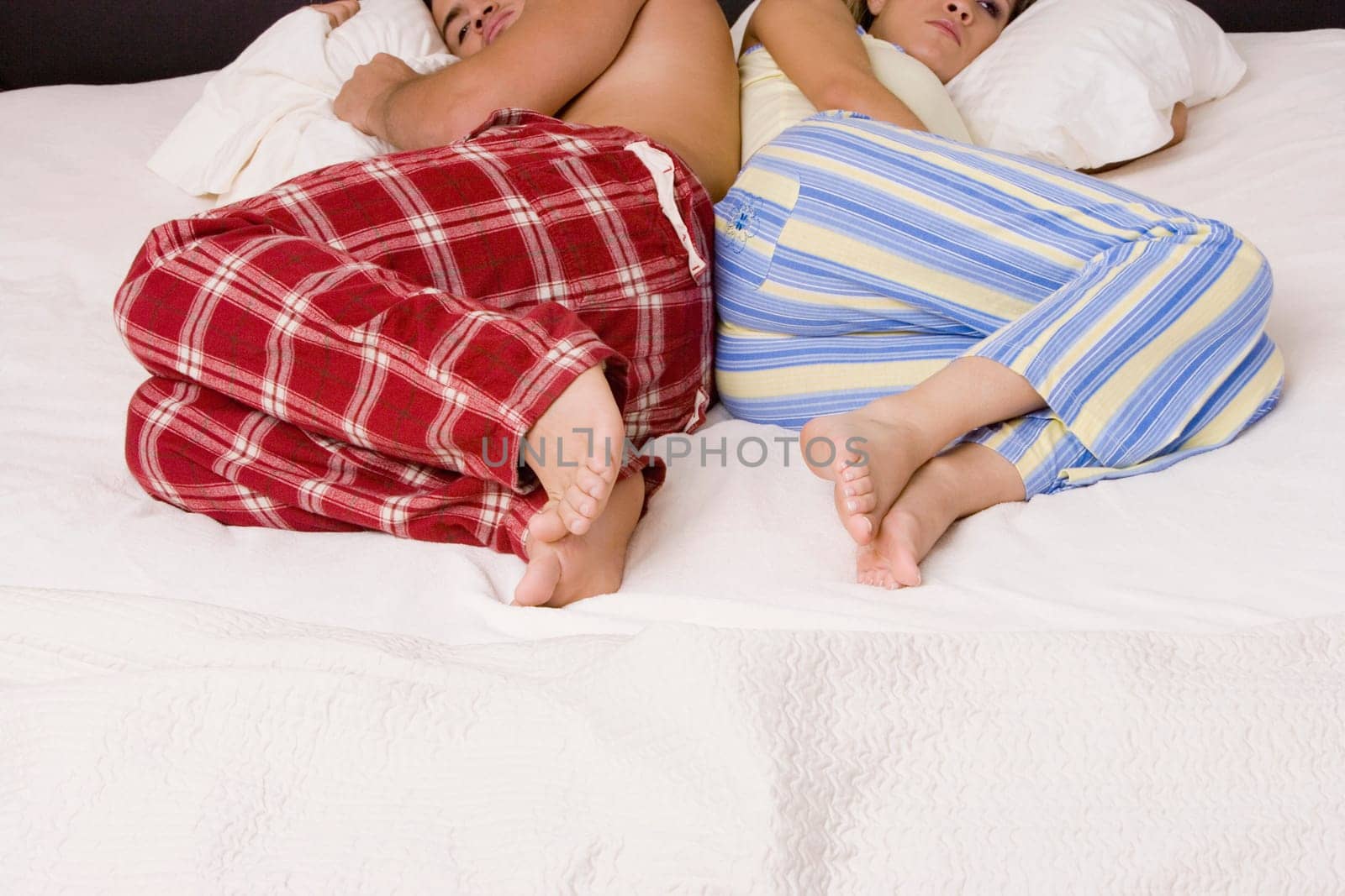 High angle view of a young couple lying back to back on the bed