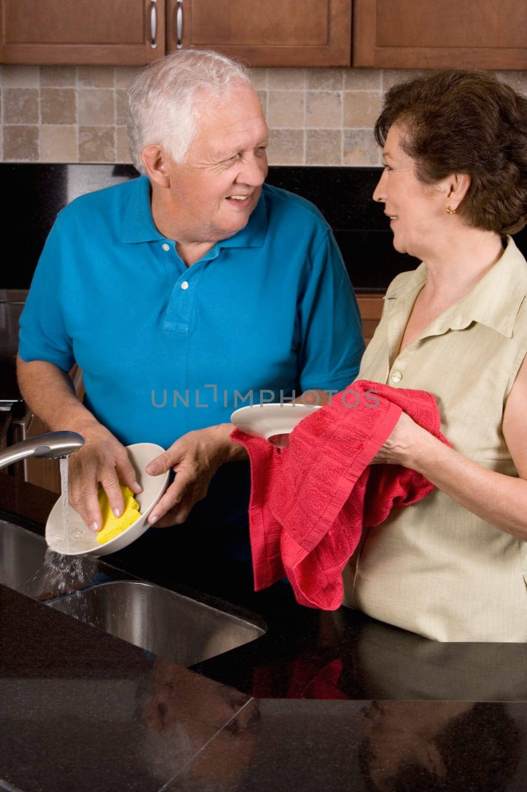 Close-up of a senior couple cleaning plates in the kitchen
