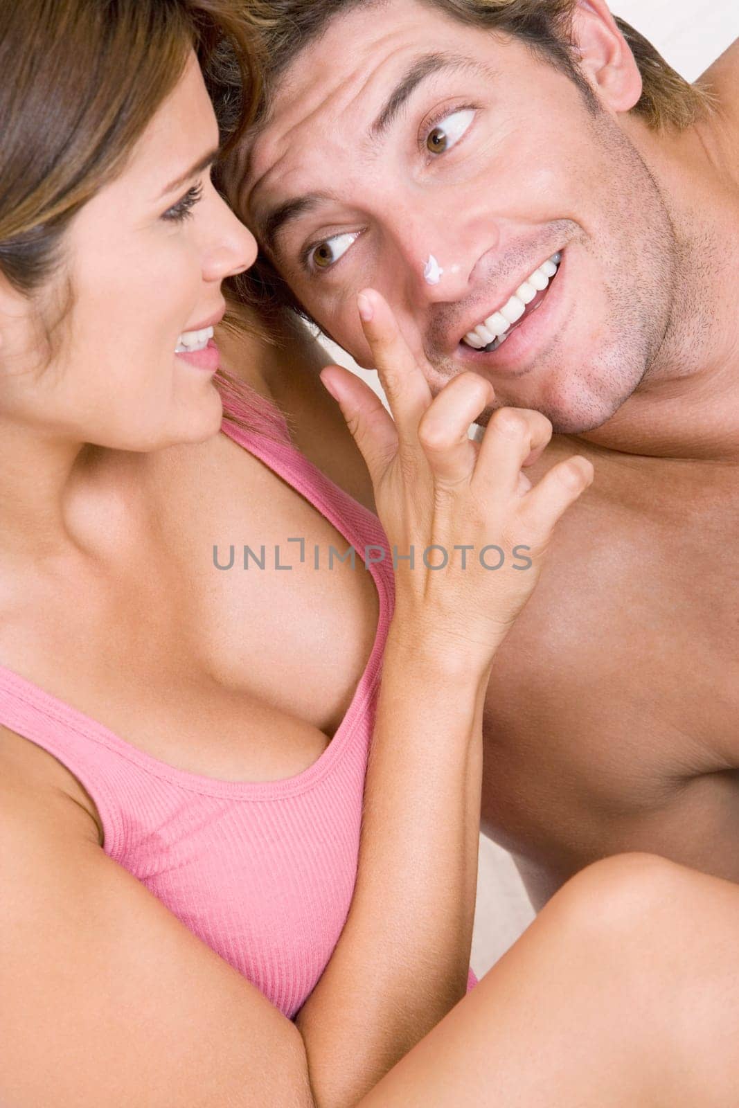 Close-up of a young woman applying lotion on a mid adult manŽs nose