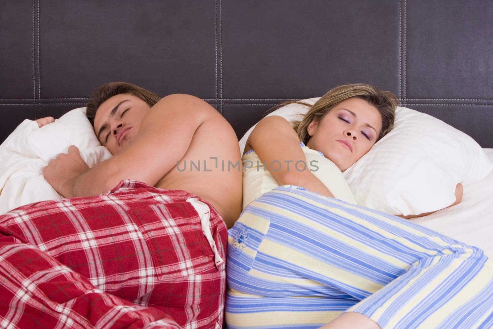 Young couple lying back to back on the bed