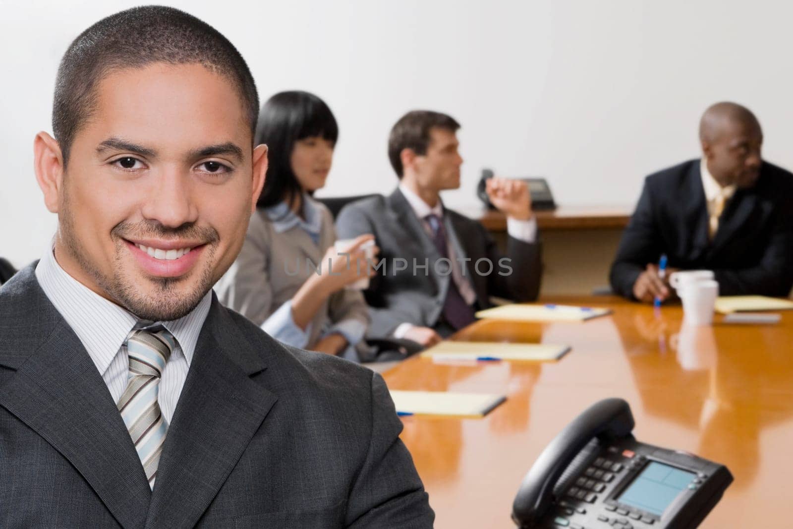 Portrait of a businessman smiling with his colleagues discussing in the background
