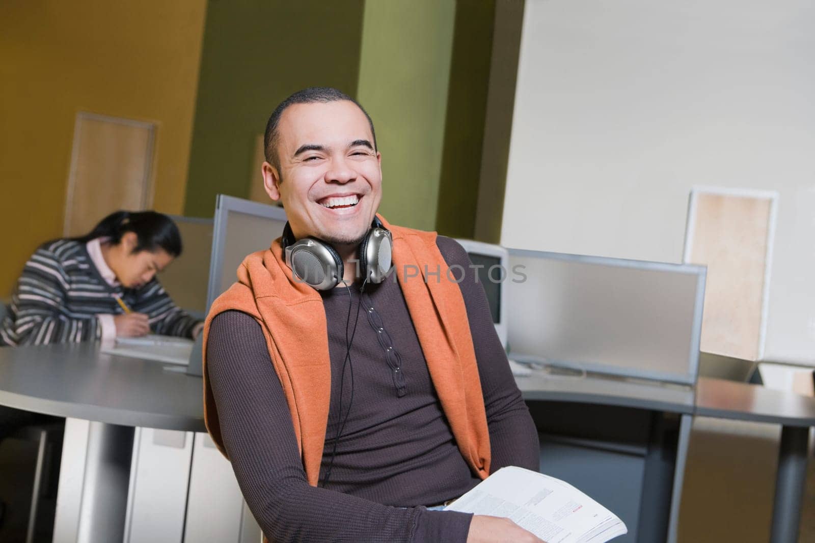 Portrait of a young man sitting in a computer lab and laughing