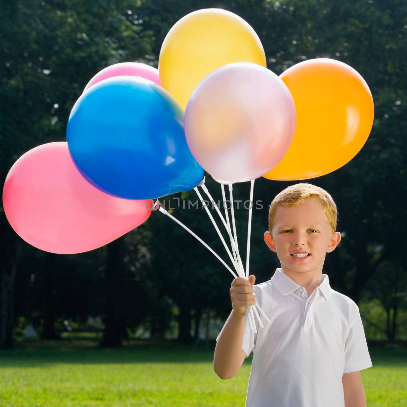 Portrait of a boy holding balloons and smiling