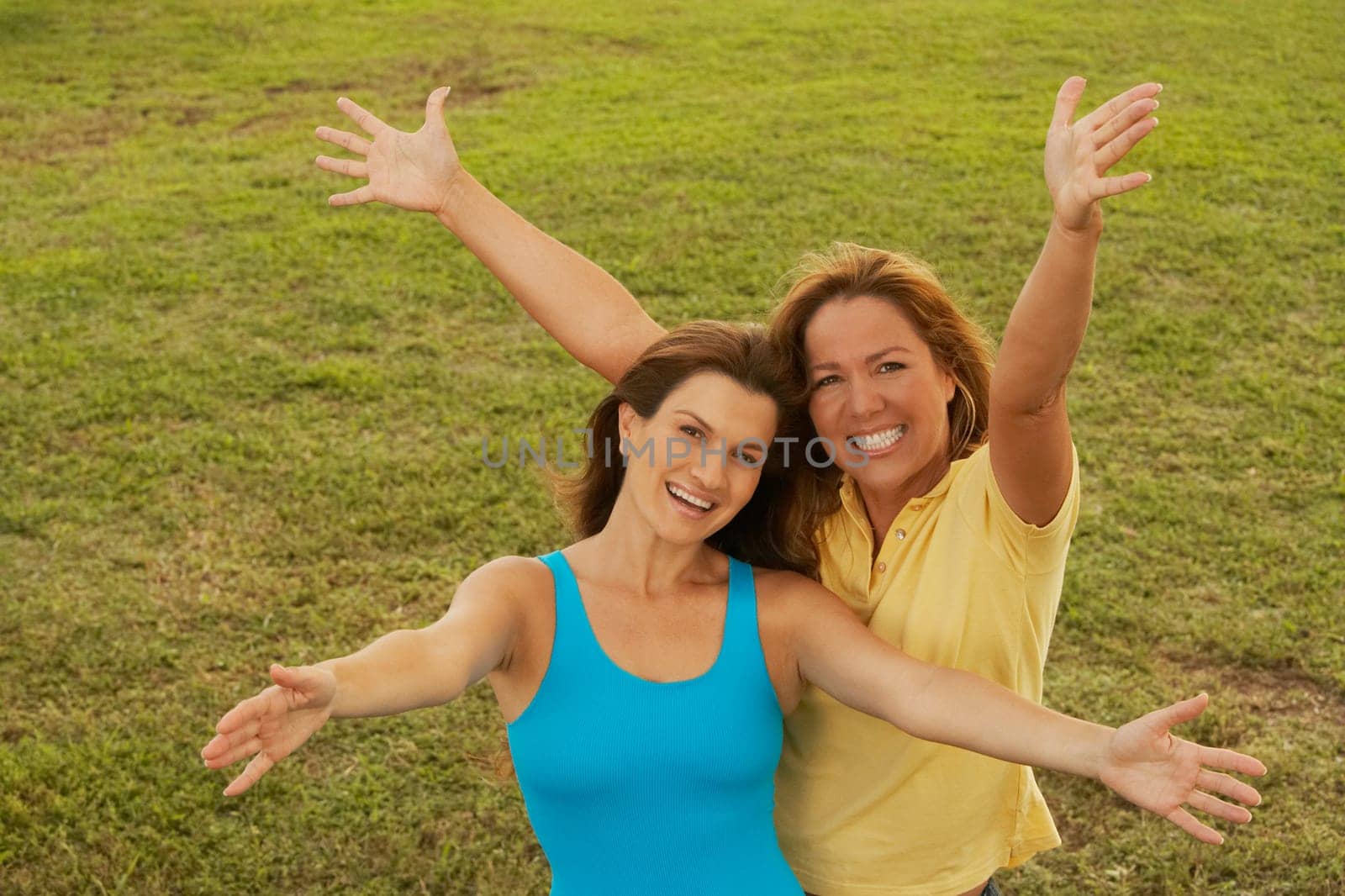 Portrait of a mid adult woman and a mature woman standing with their arms outstretched